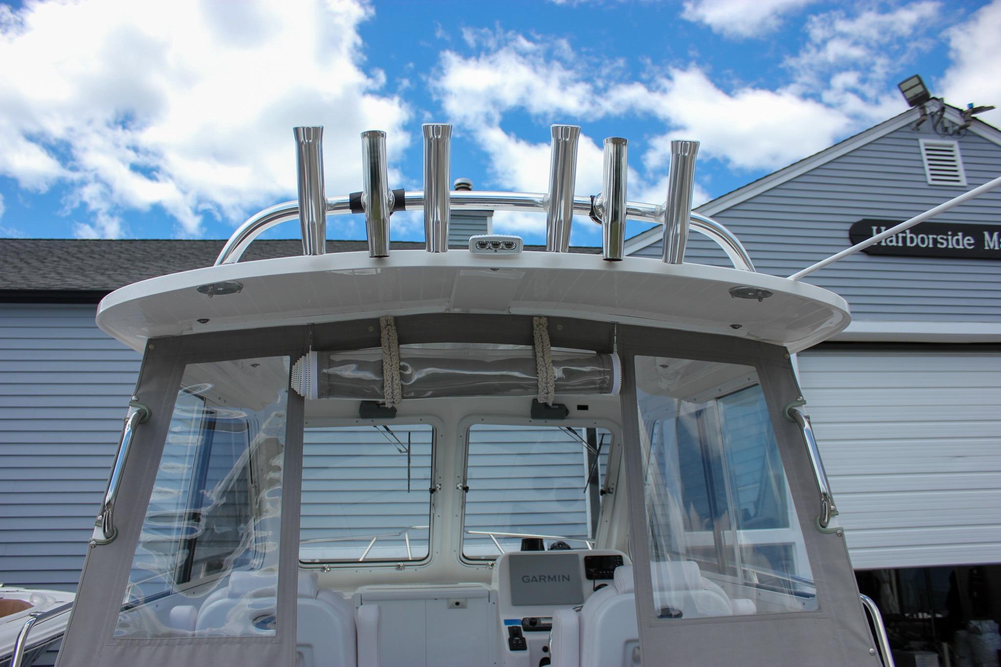 2022 NorthCoast 235 Cabin boat with rod holders, clear skies, and marina backdrop.
