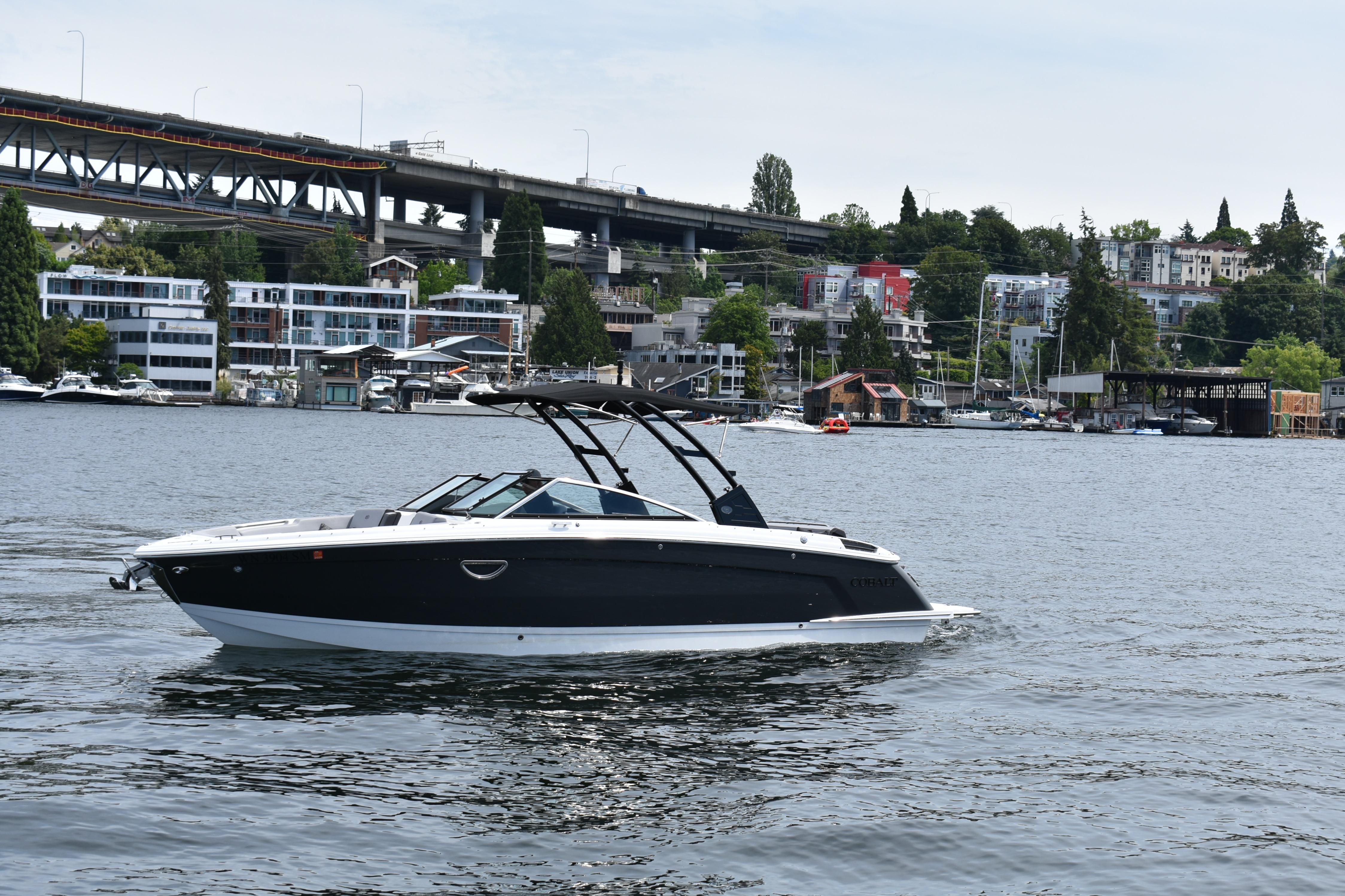 2023 Cobalt R8 boat cruising on a scenic urban waterway with bridge and buildings.