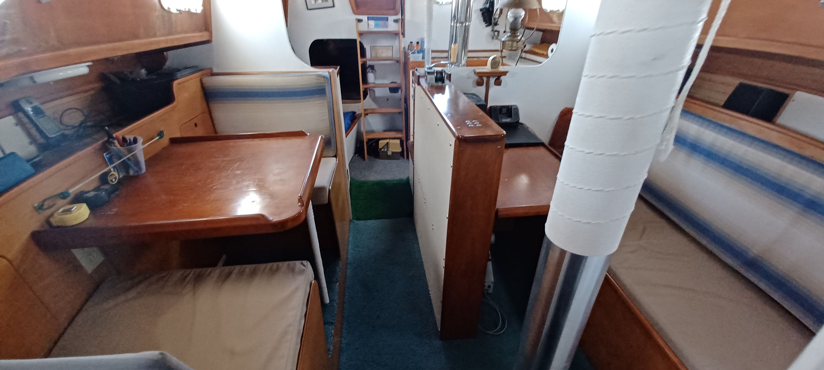 Interior view of a sailboat with wooden furnishings and seating areas.