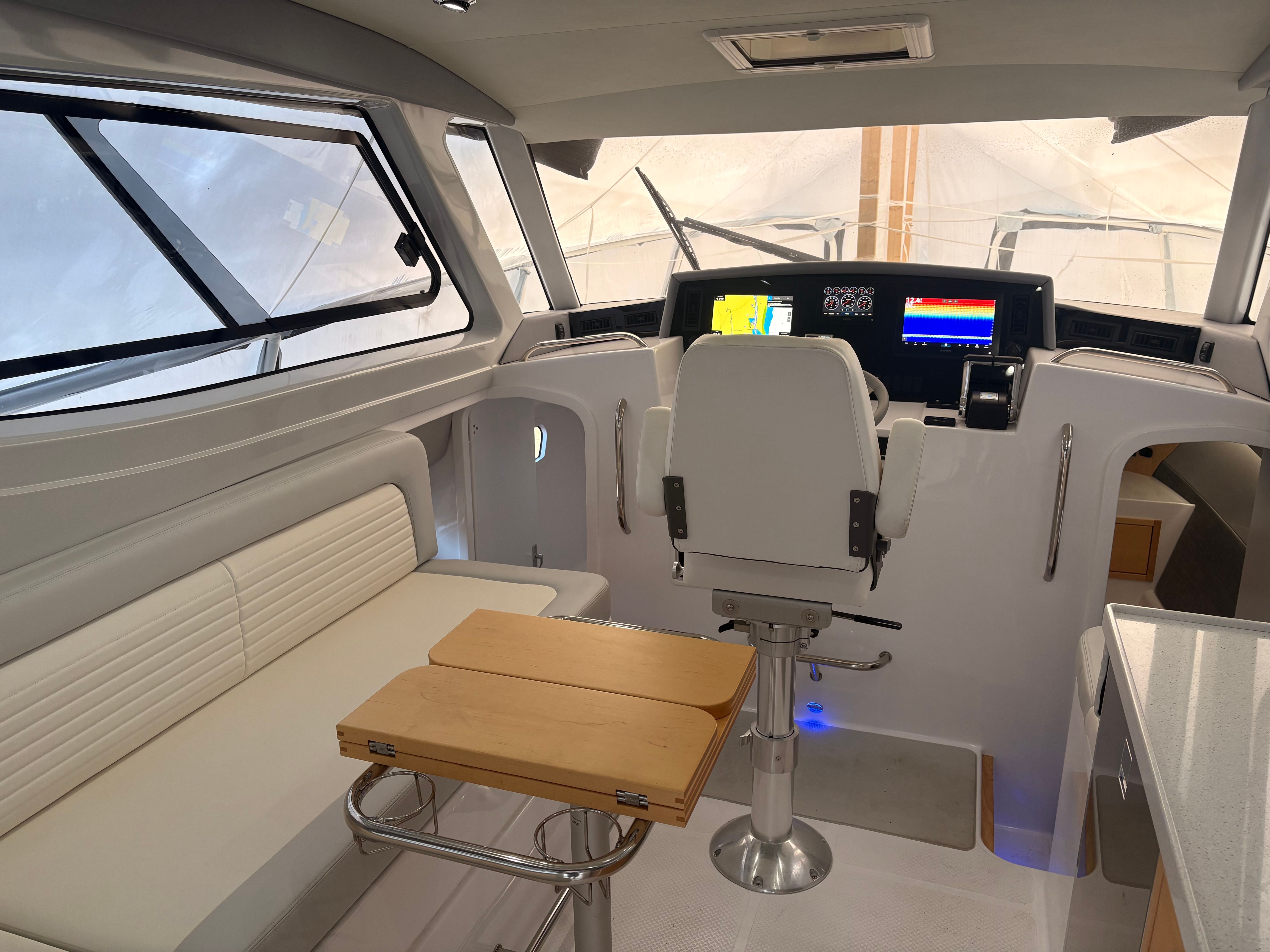 Interior of a modern yacht with helm, seating, and table.