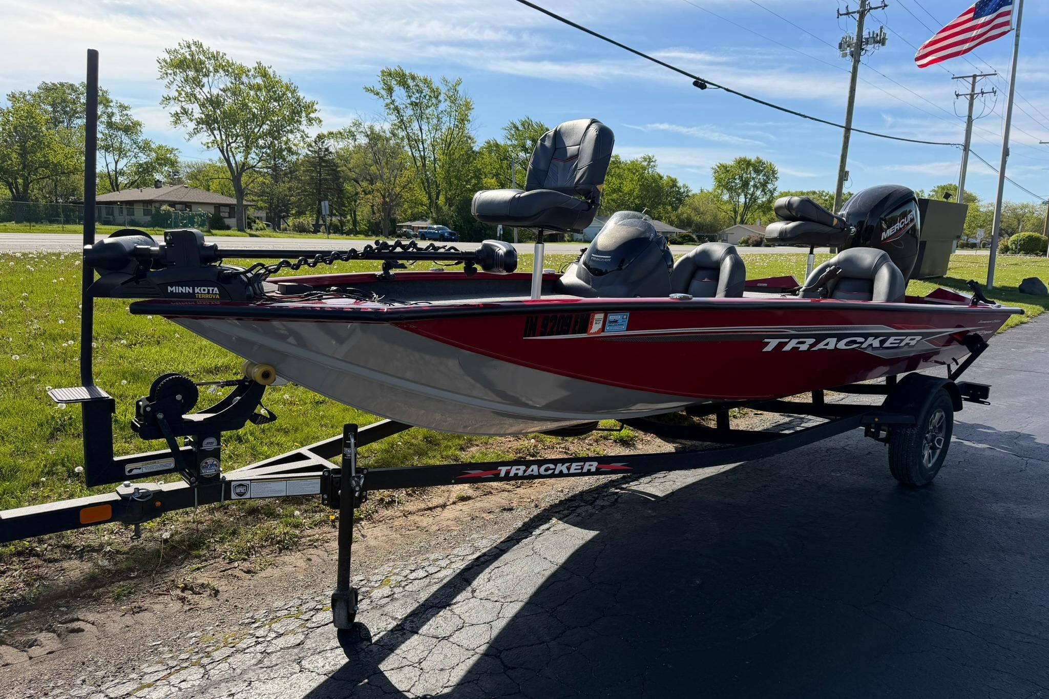 2024 Tracker Pro Team 175 TXW boat on trailer, parked outdoors with American flag.