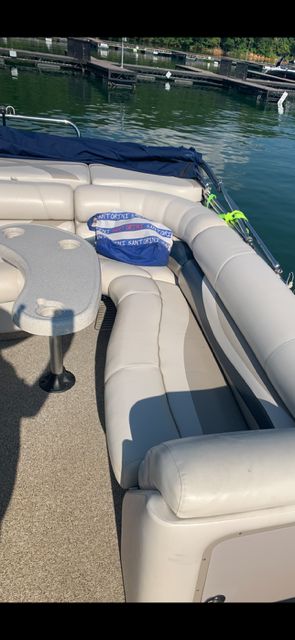 The image shows a boat deck with beige seating and a small table.