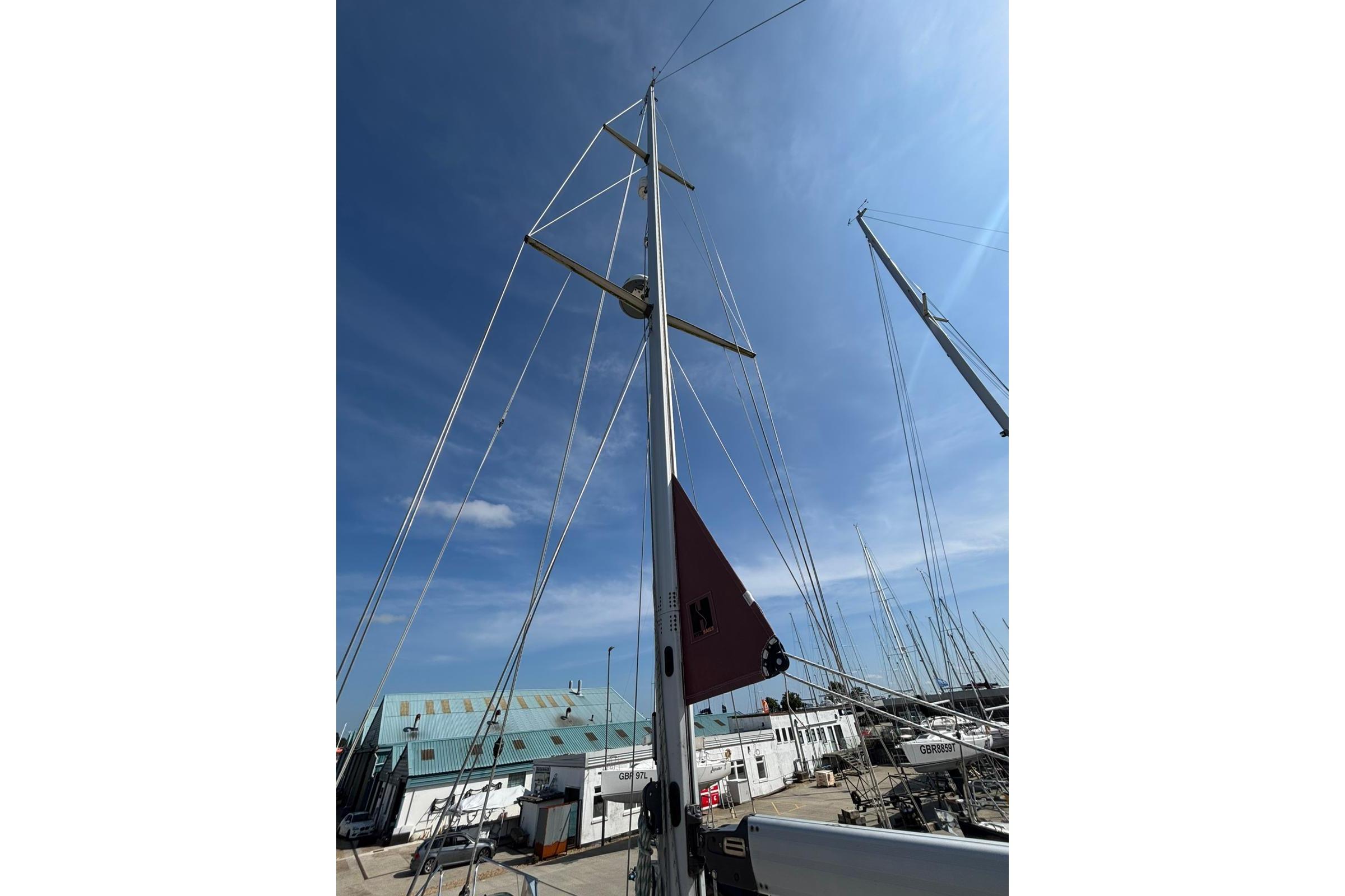 Tall mast of a 1997 Najad 361 sailboat against a clear blue sky.