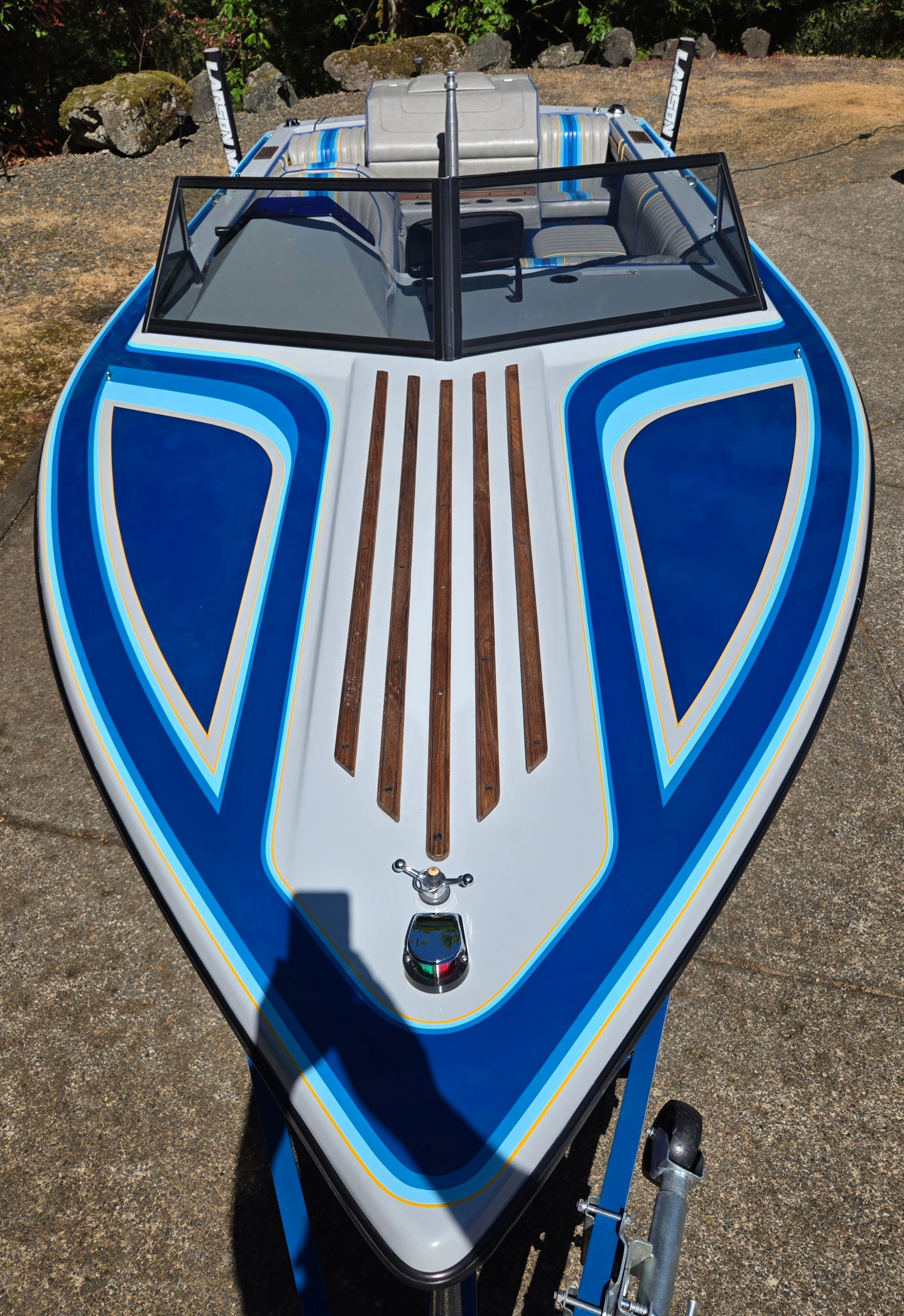 A 1990 Sanger Ski Sanger boat with blue and white paint and wood accents on the deck.