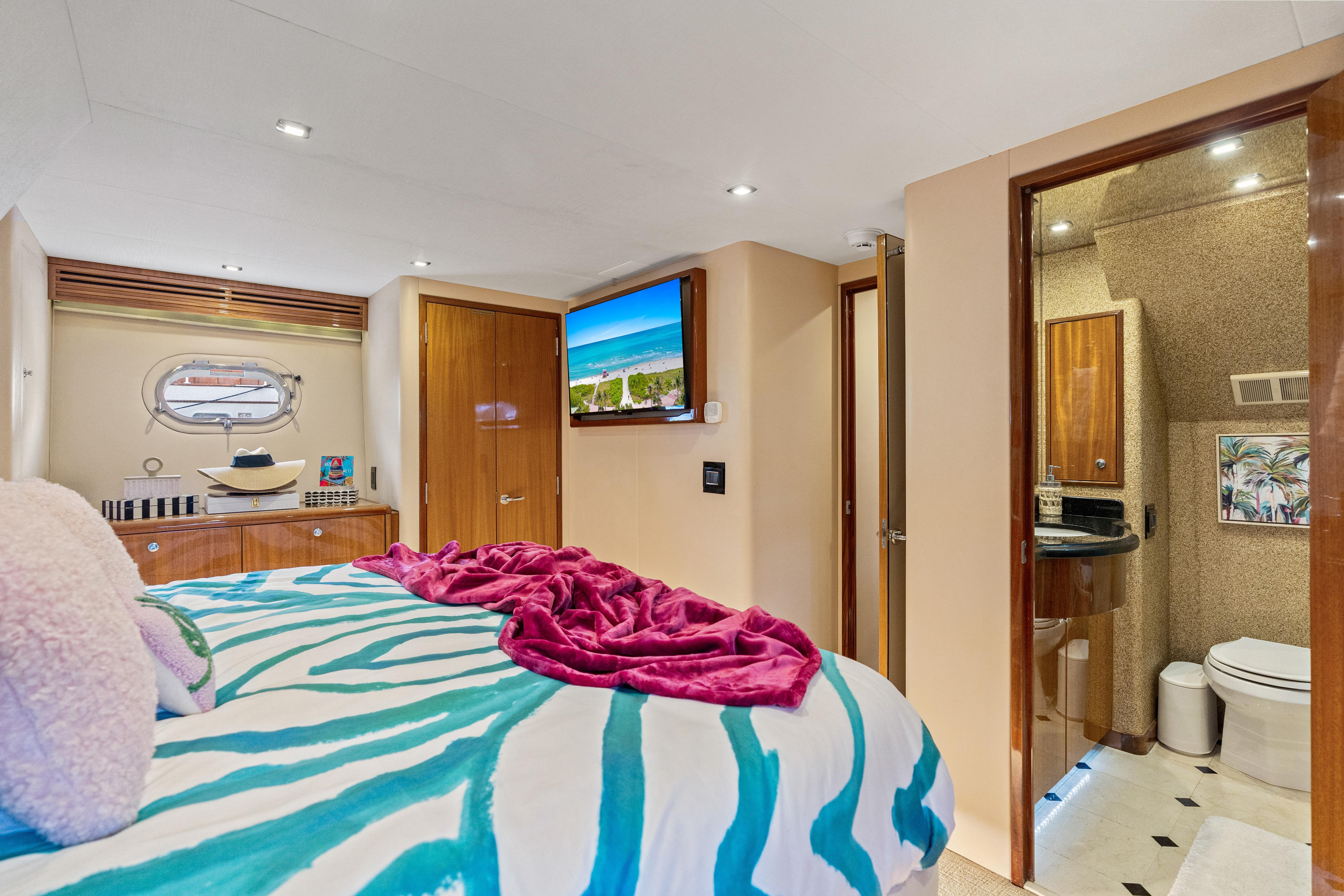 Luxurious bedroom and bathroom in a 2008 Hatteras 64 Motor Yacht, featuring modern decor.