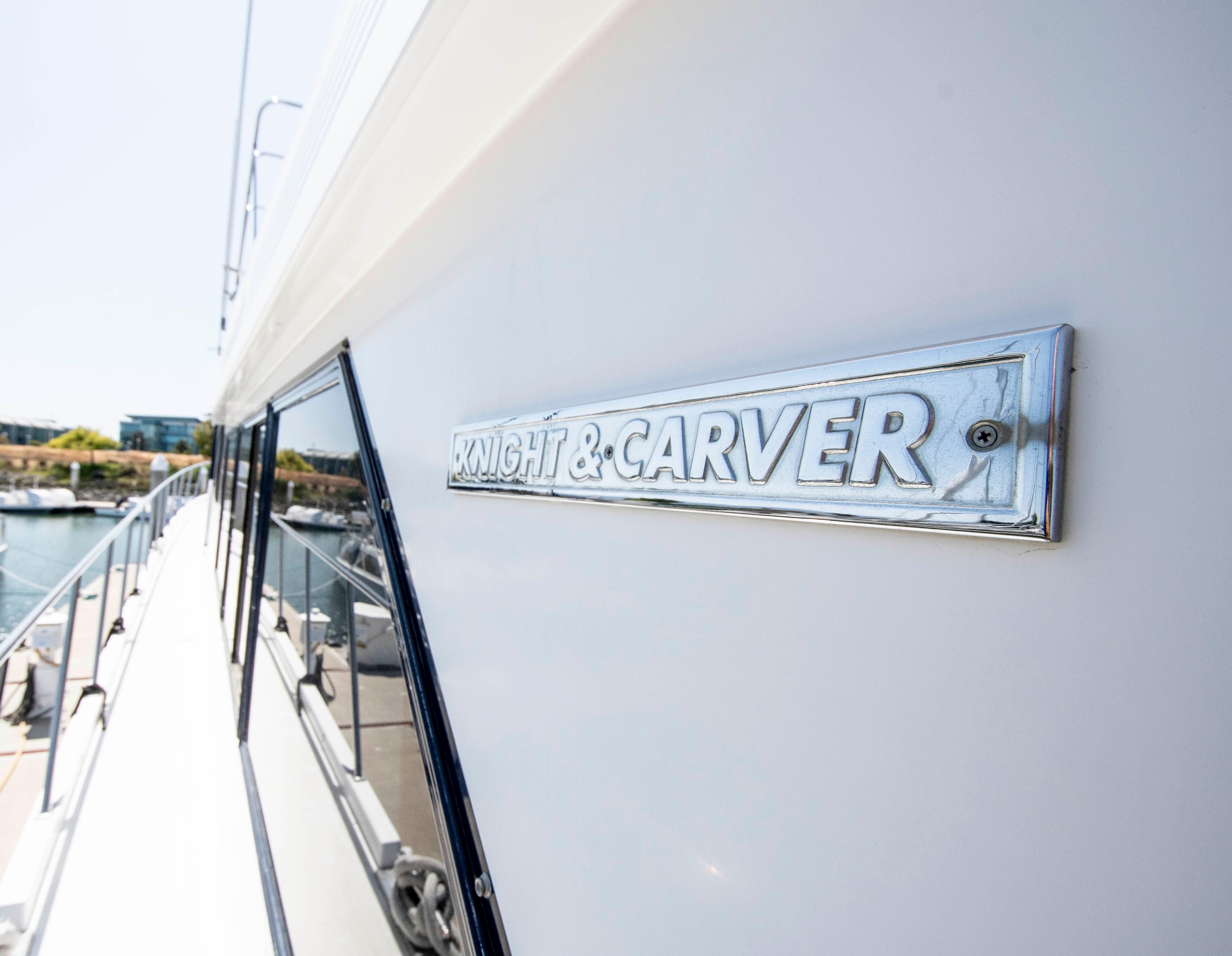 1988 Knight & Carver Motoryacht with logo, docked by the water.