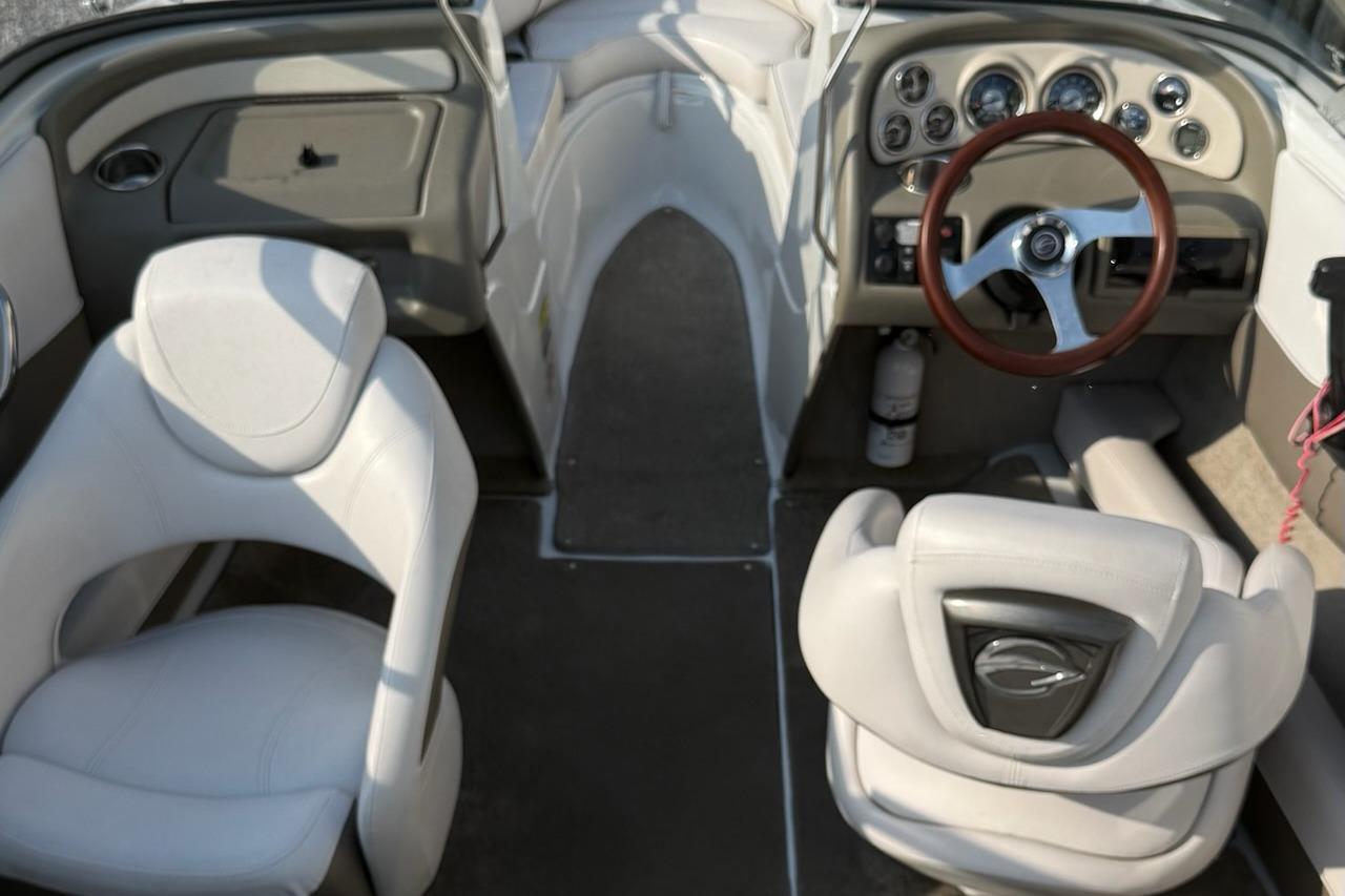 Interior of a 2012 195 SS boat featuring white seats and a wooden steering wheel.