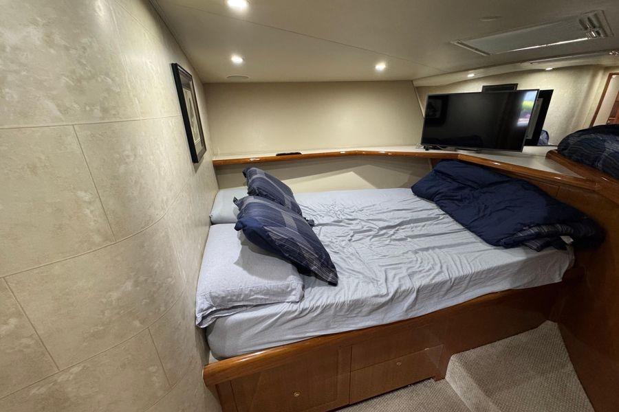 Cozy bedroom interior of 2002 Viking 61 Enclosed Bridge yacht with modern amenities.