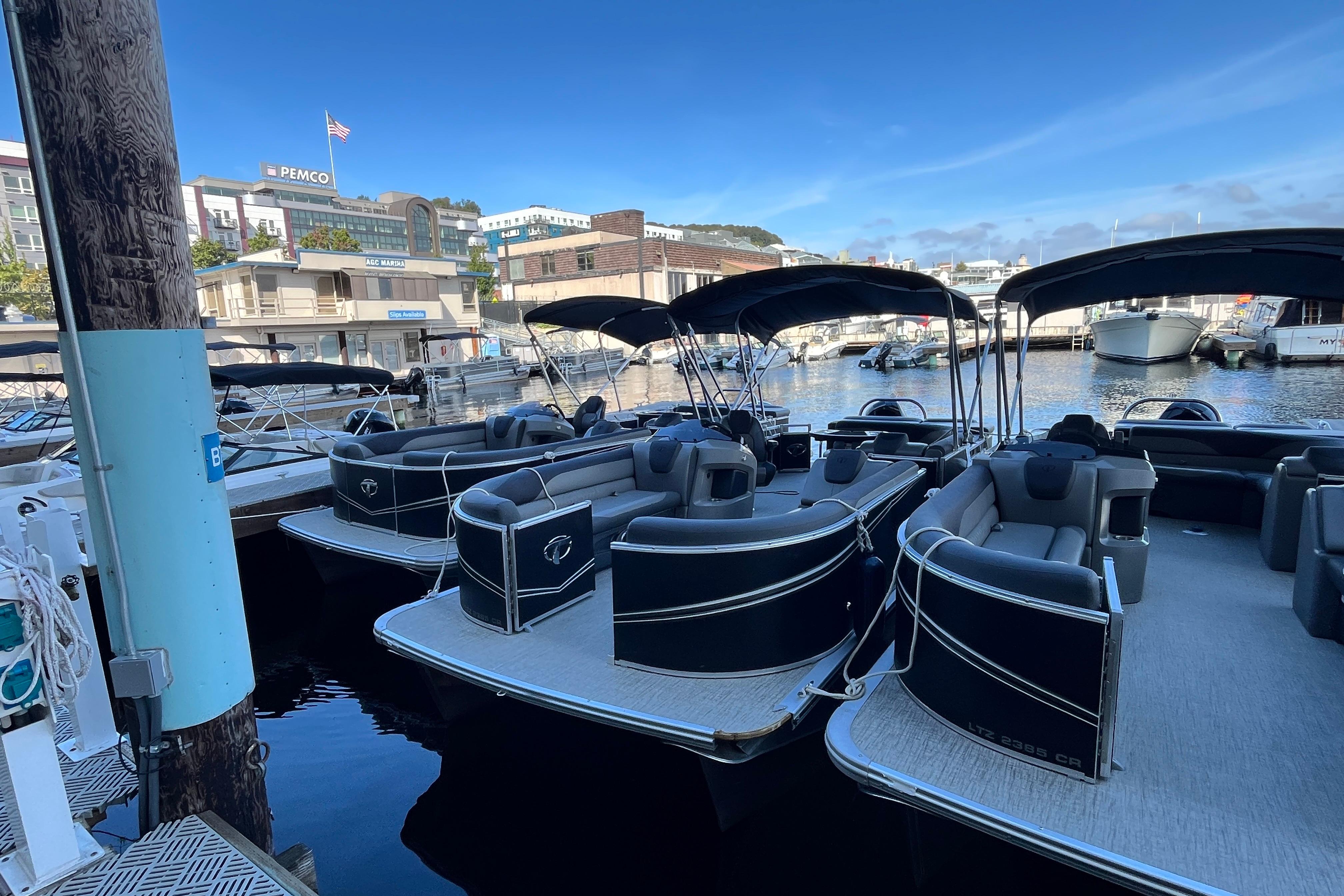 2023 Tahoe Pontoon LTZ Cruise boats docked at a marina under clear blue skies.