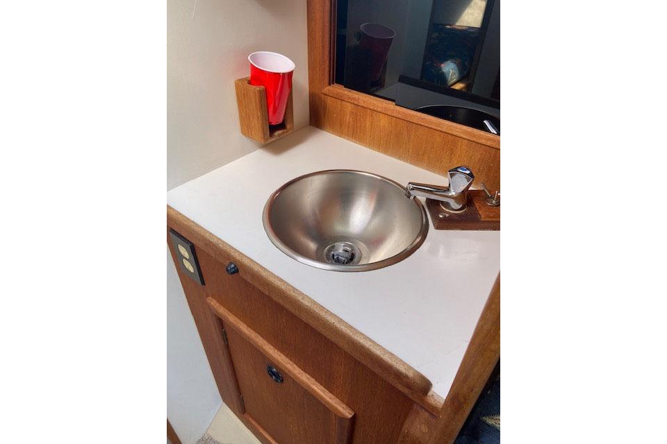 1977 C&C 29 yacht interior with stainless steel sink and wooden cabinetry.