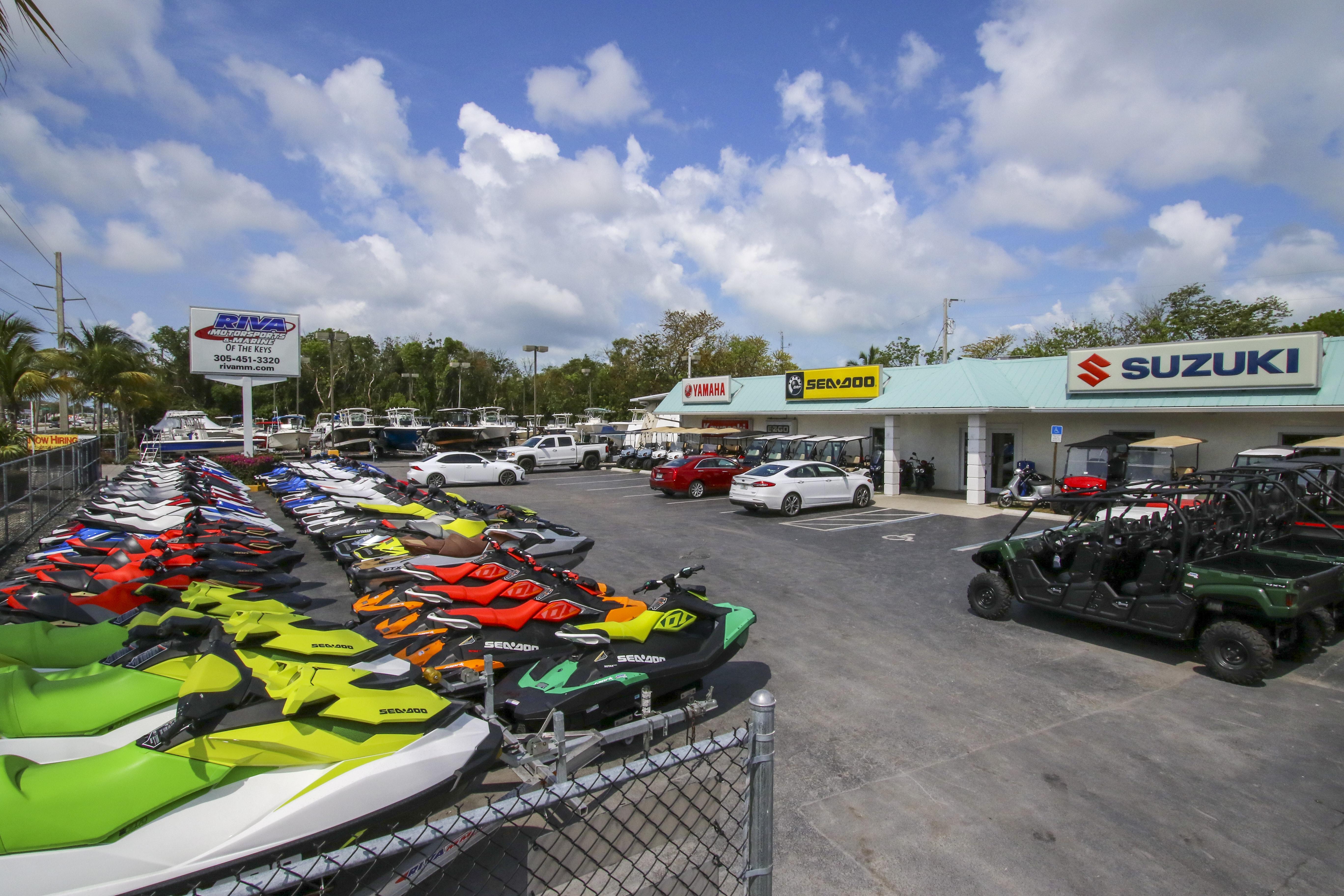 Outdoor dealership with colorful jet skis and Suzuki vehicles under a blue sky.