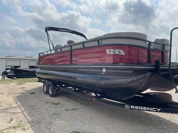 2023 Regency 250DL3 pontoon boat on trailer, red and black design, parked outdoors.