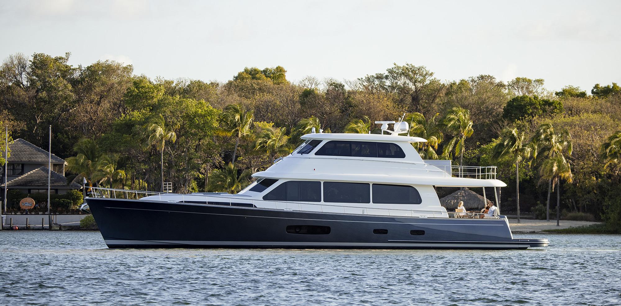 2026 Grand Banks GB 85 yacht cruising on a serene waterway with lush greenery.