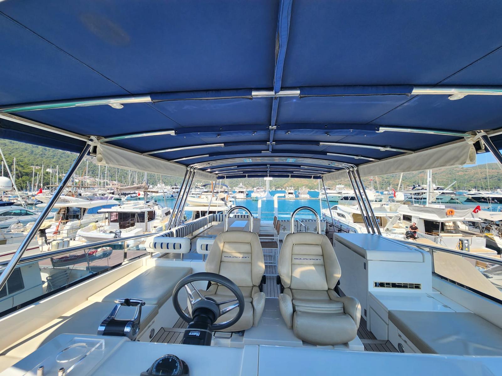 Flybridge view of 2012 Fairline Squadron 65 yacht, featuring helm and seating area in marina.