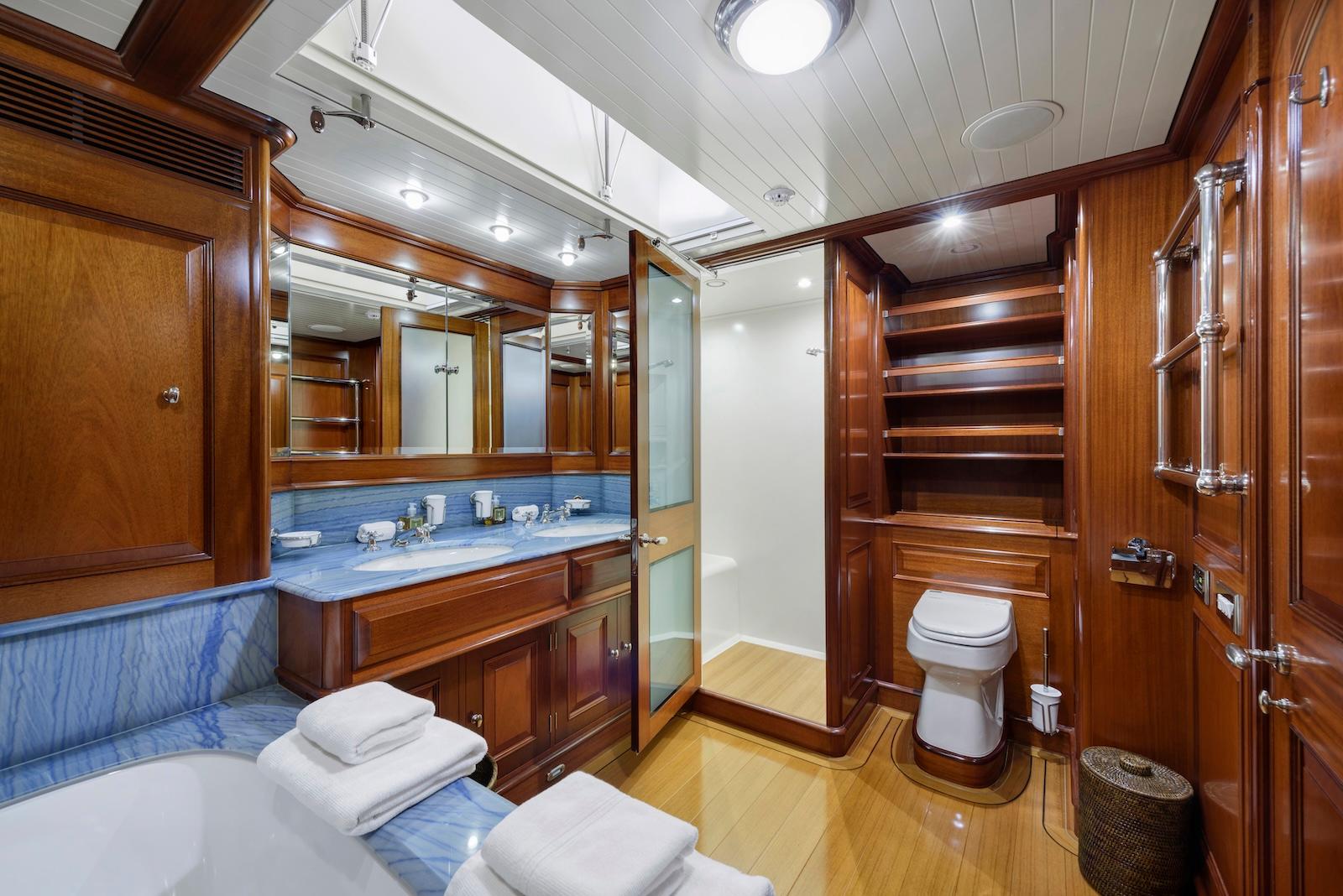 Luxurious wooden bathroom interior on 2007 Royal Huisman Schooner yacht, featuring elegant fixtures and blue accents.