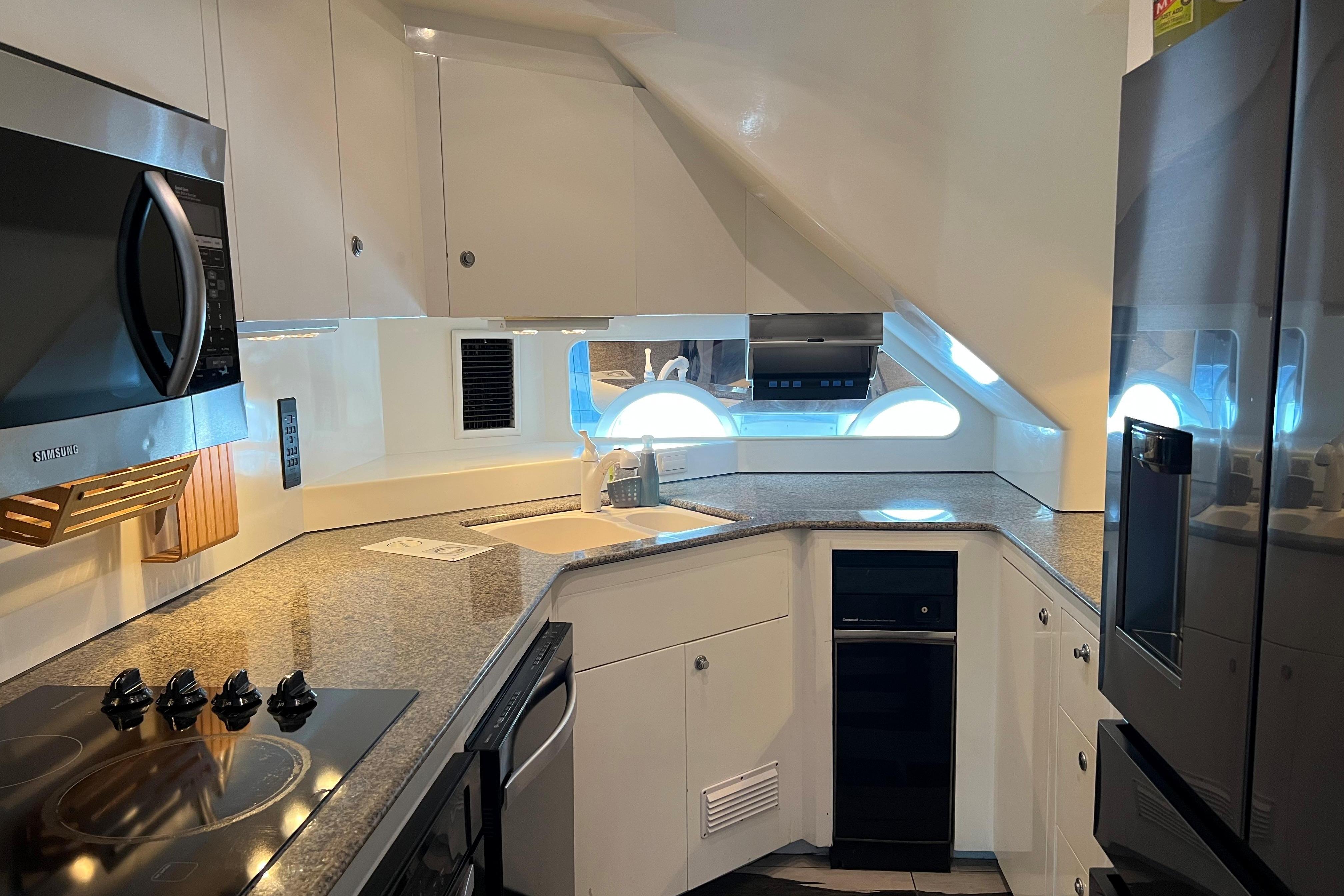 Modern kitchen interior on a 1996 Monte Fino 92 yacht, featuring sleek appliances and granite countertops.