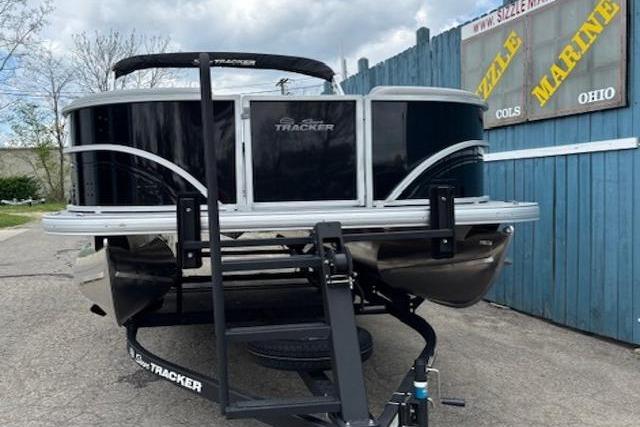 2026 Sun Tracker Party Barge 20 DLX pontoon boat on trailer, parked near blue fence.