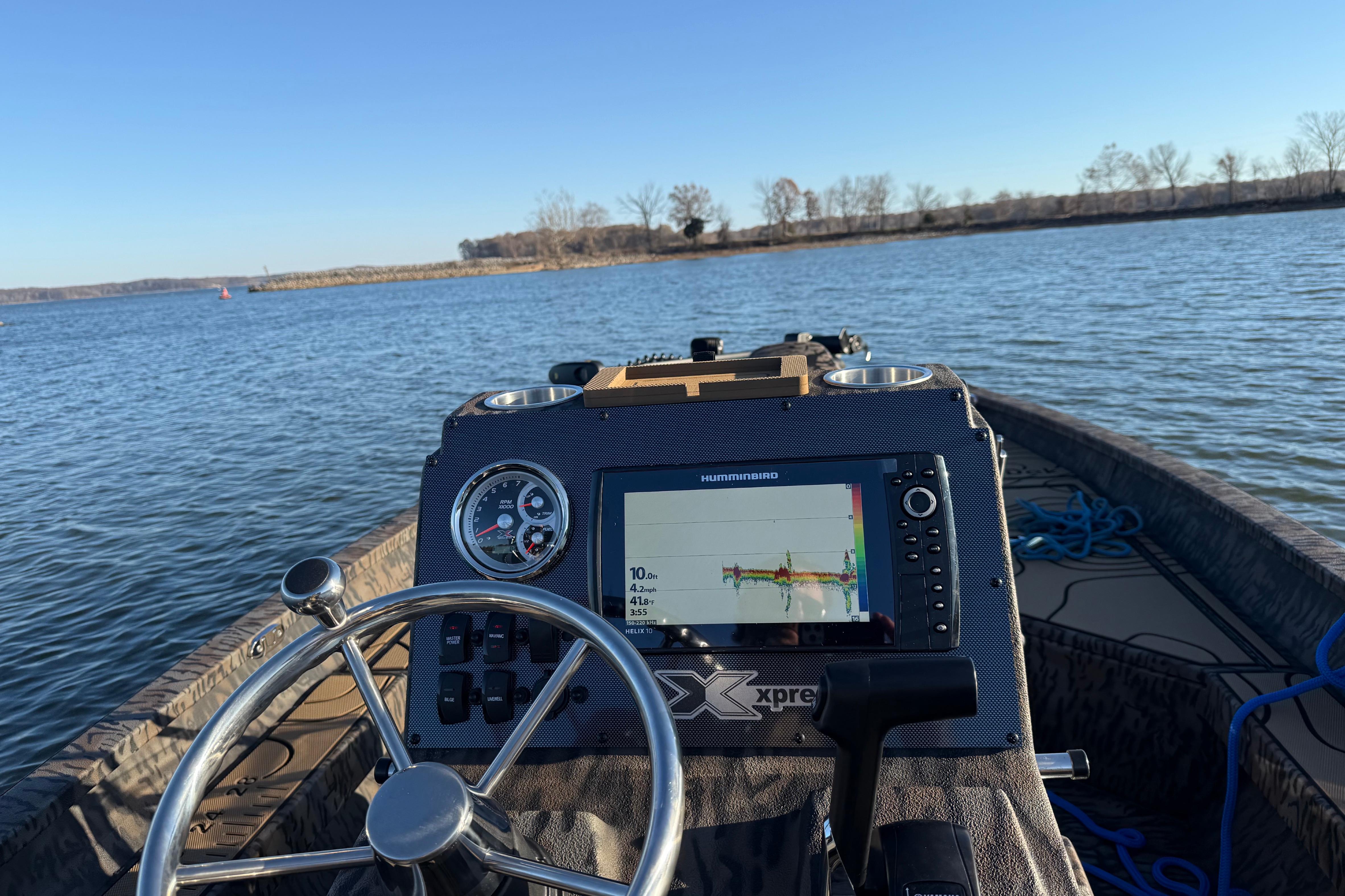 Steering console of 2025 Xpress H22B Bay boat on a calm lake.