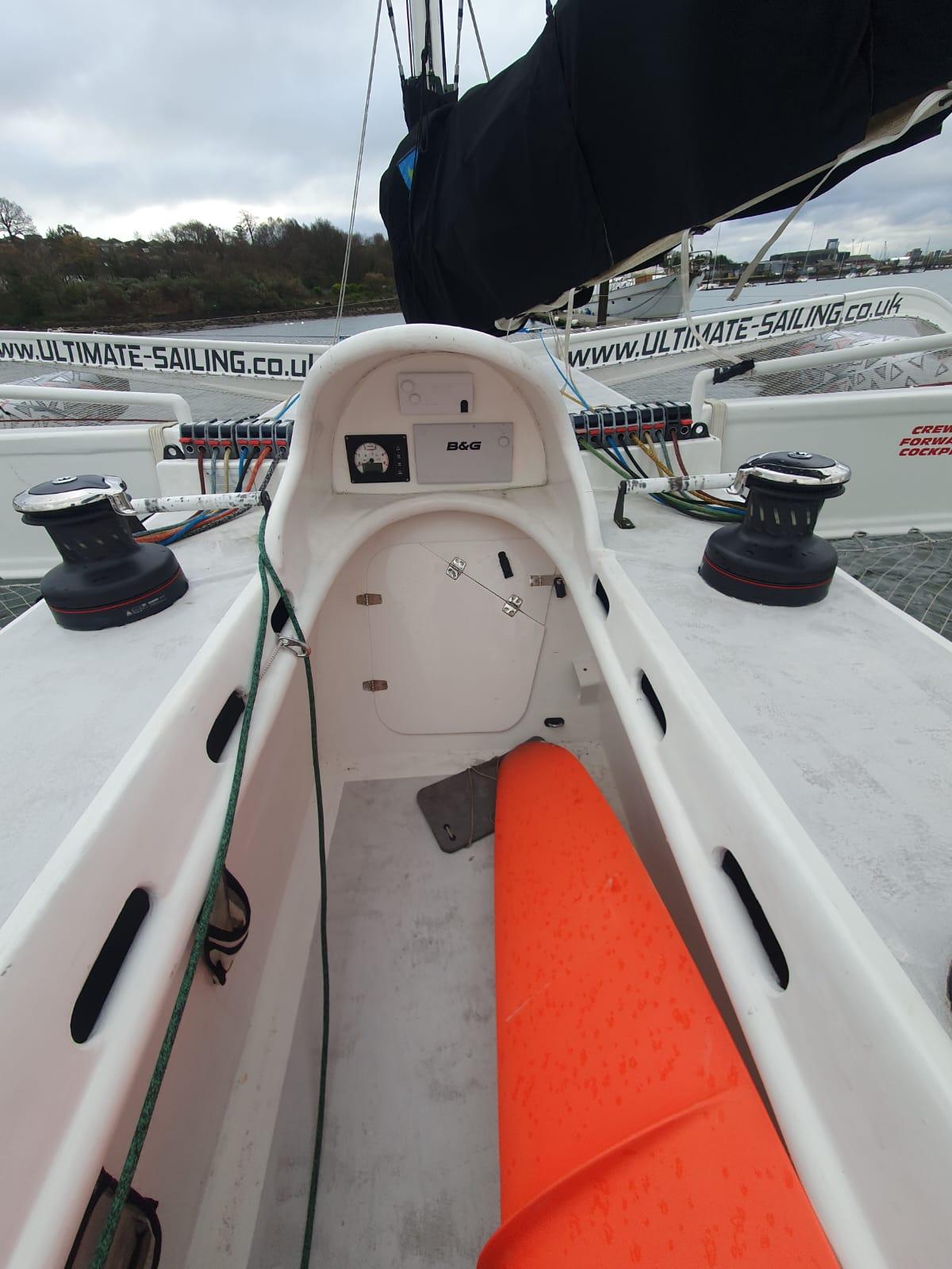 2002 Custom Trimaran cockpit with orange seat, sailing equipment, and visible branding.