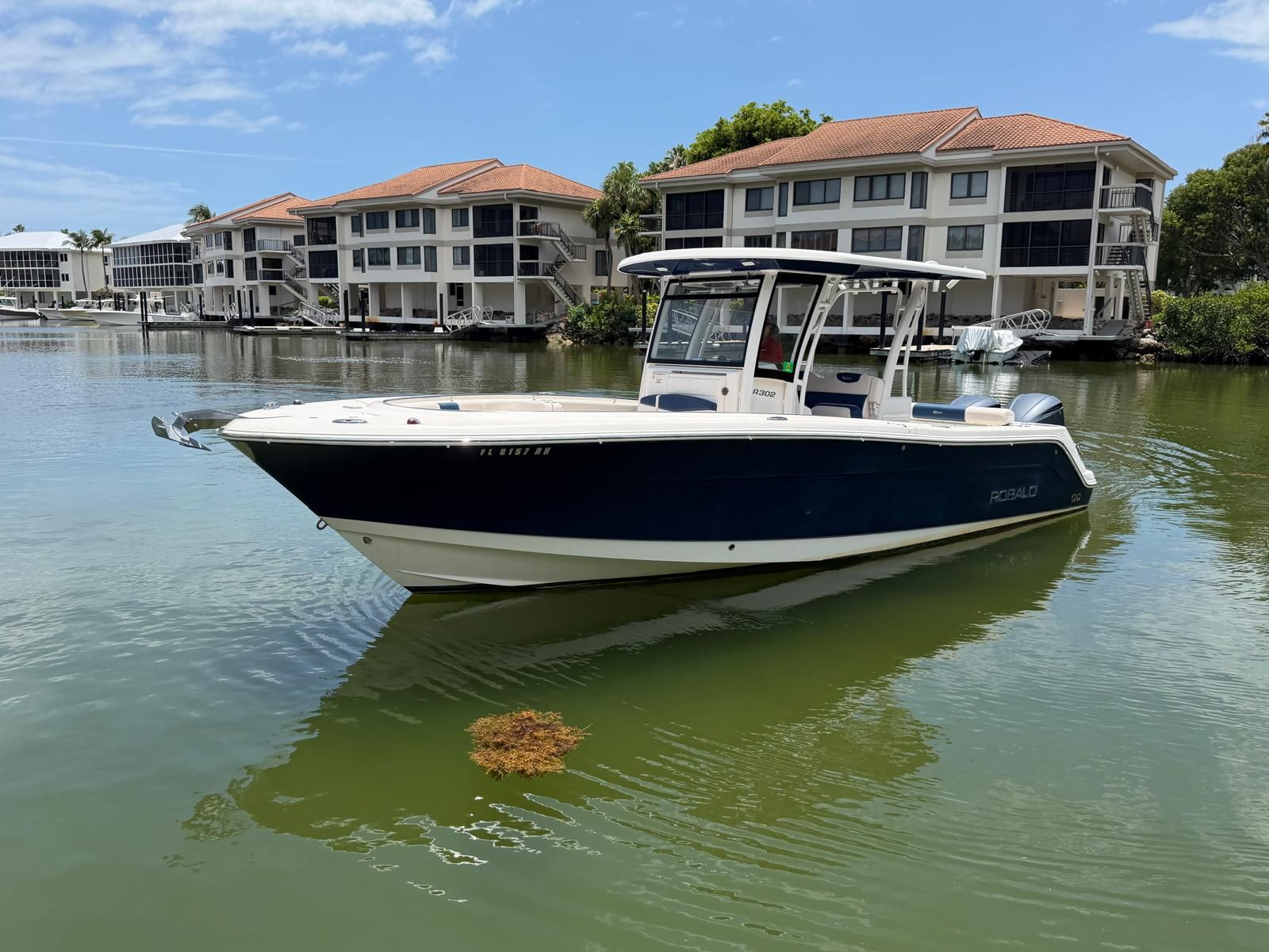 2017 Robalo R302 Center Console boat on calm water near buildings.