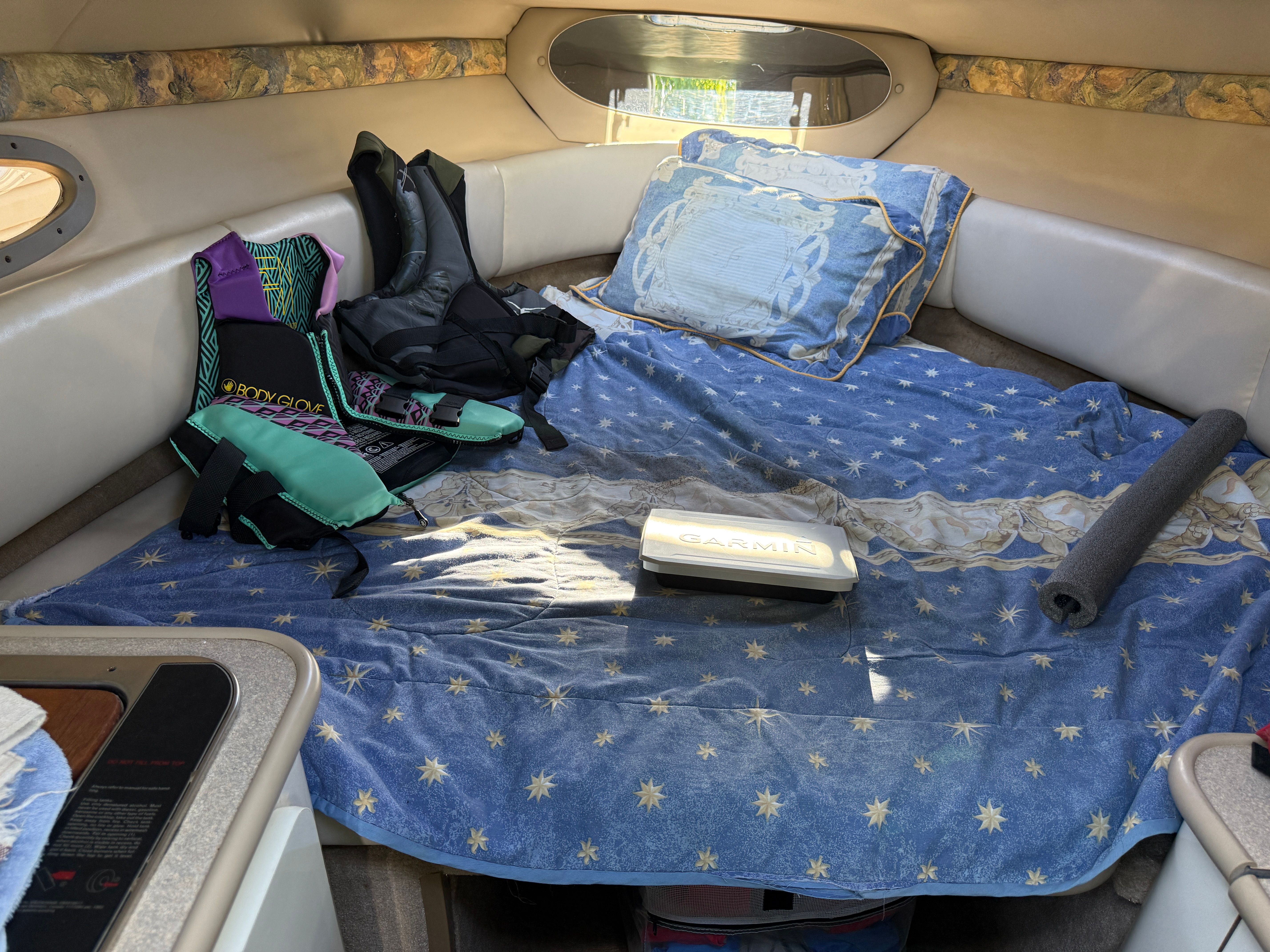 Interior of a 1999 Custom 2335 Cuddy cabin with bed and gear.