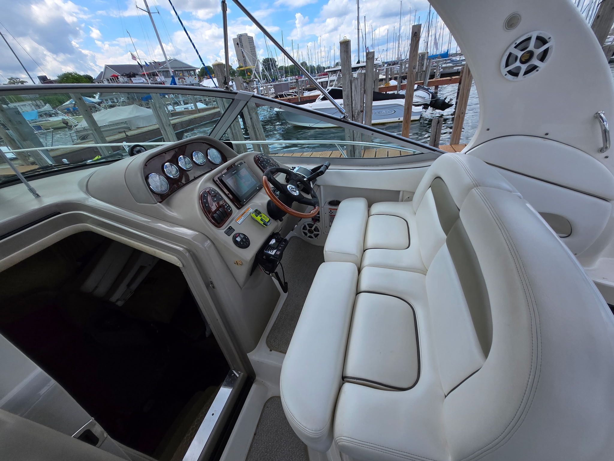 The cockpit of a 2006 Sea Ray 300 Sundancer with white seating and a helm station.
