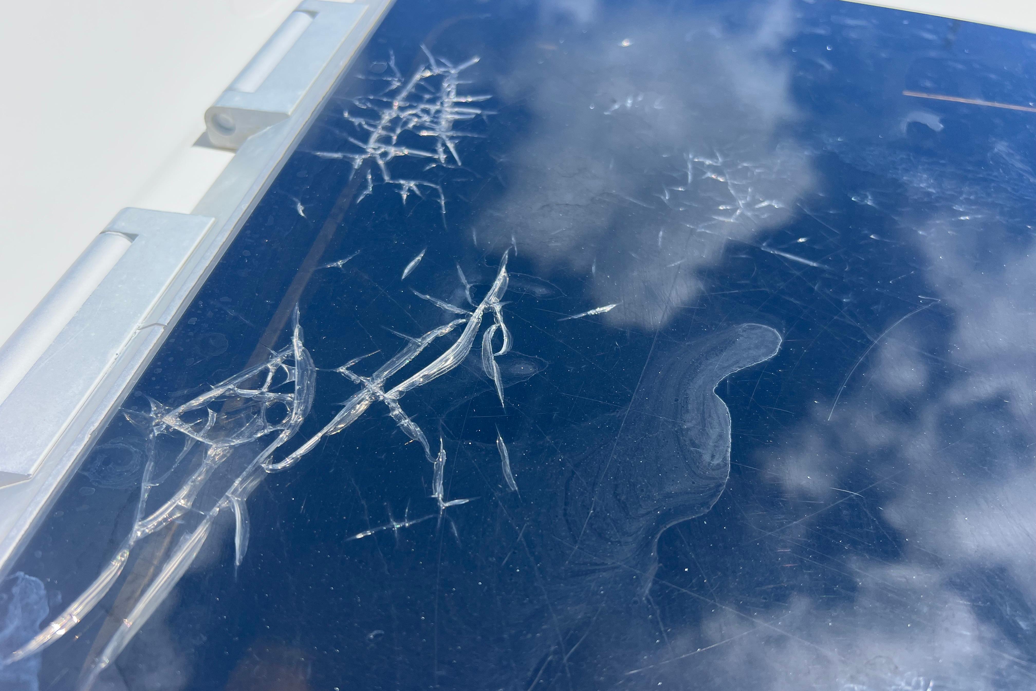 Cracked glass surface on 2004 Pursuit 2870 Walkaround boat, reflecting cloudy sky.