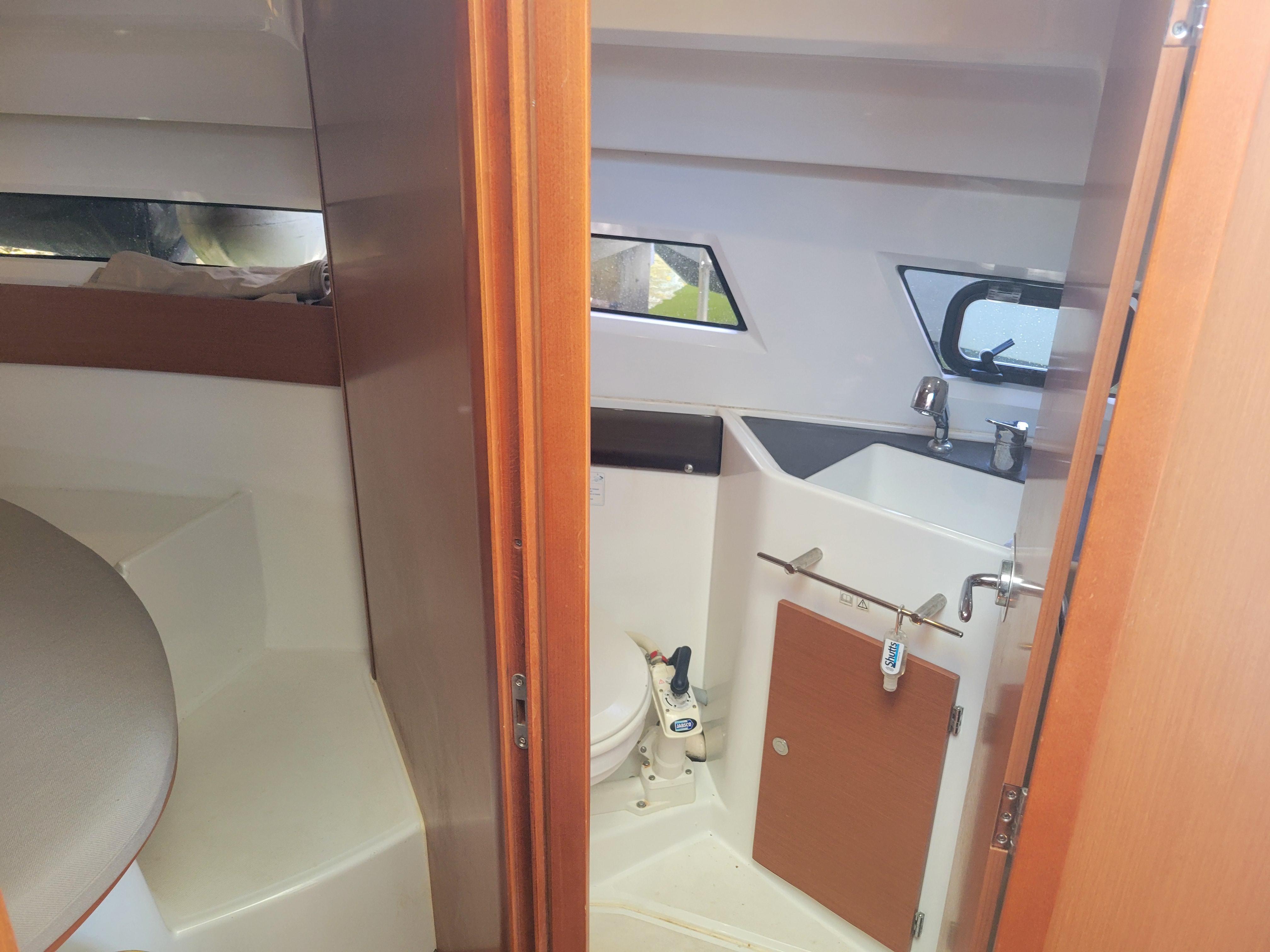 2016 Jeanneau Merry Fisher 855 interior with bathroom and seating area.