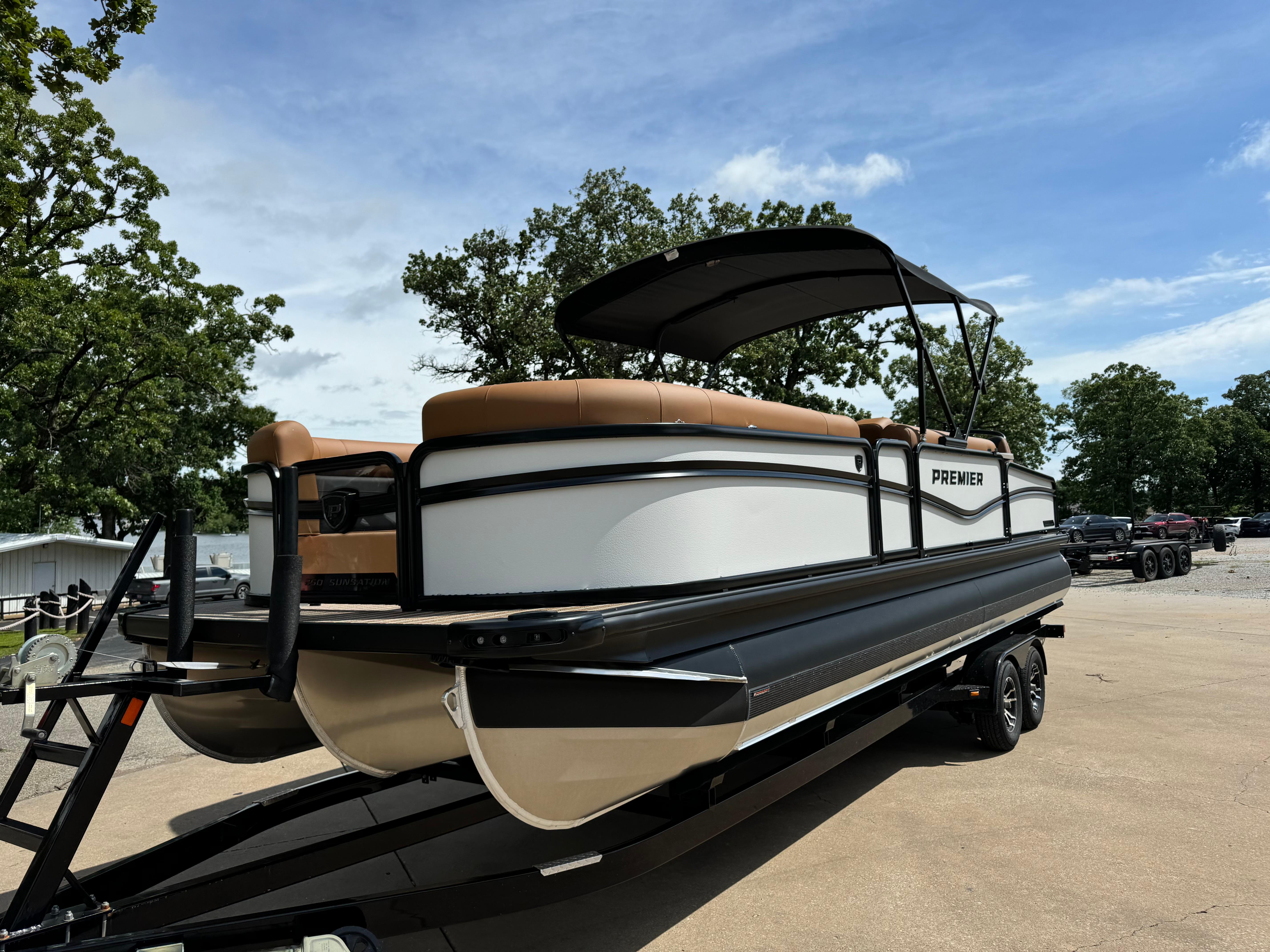 2025 Premier 250 Sunsation Rear Social pontoon boat on trailer, under clear blue sky.