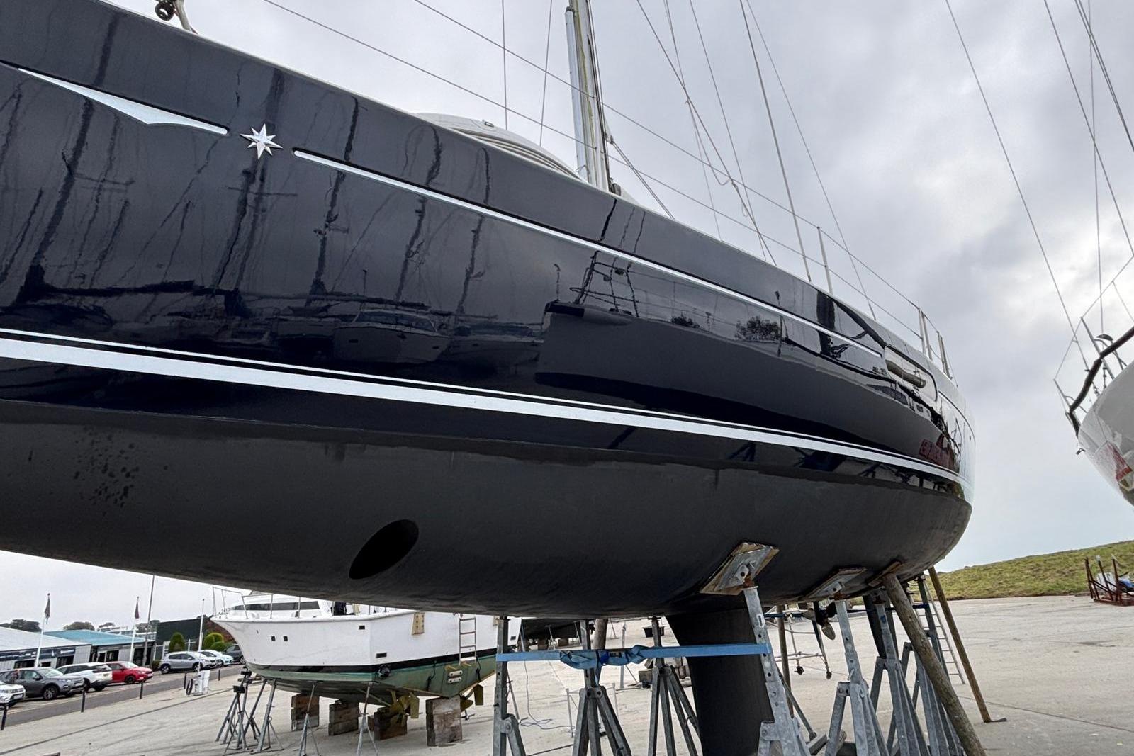 2011 Jeanneau Sun Odyssey 45 DS sailboat on stands, side view, overcast sky.