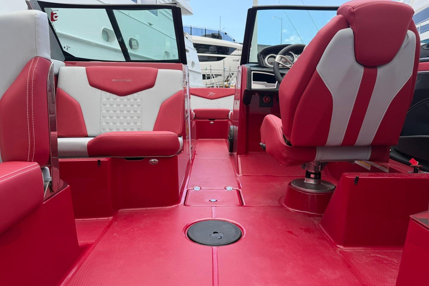 2023 MasterCraft X24 boat interior with red and white seating and modern dashboard.