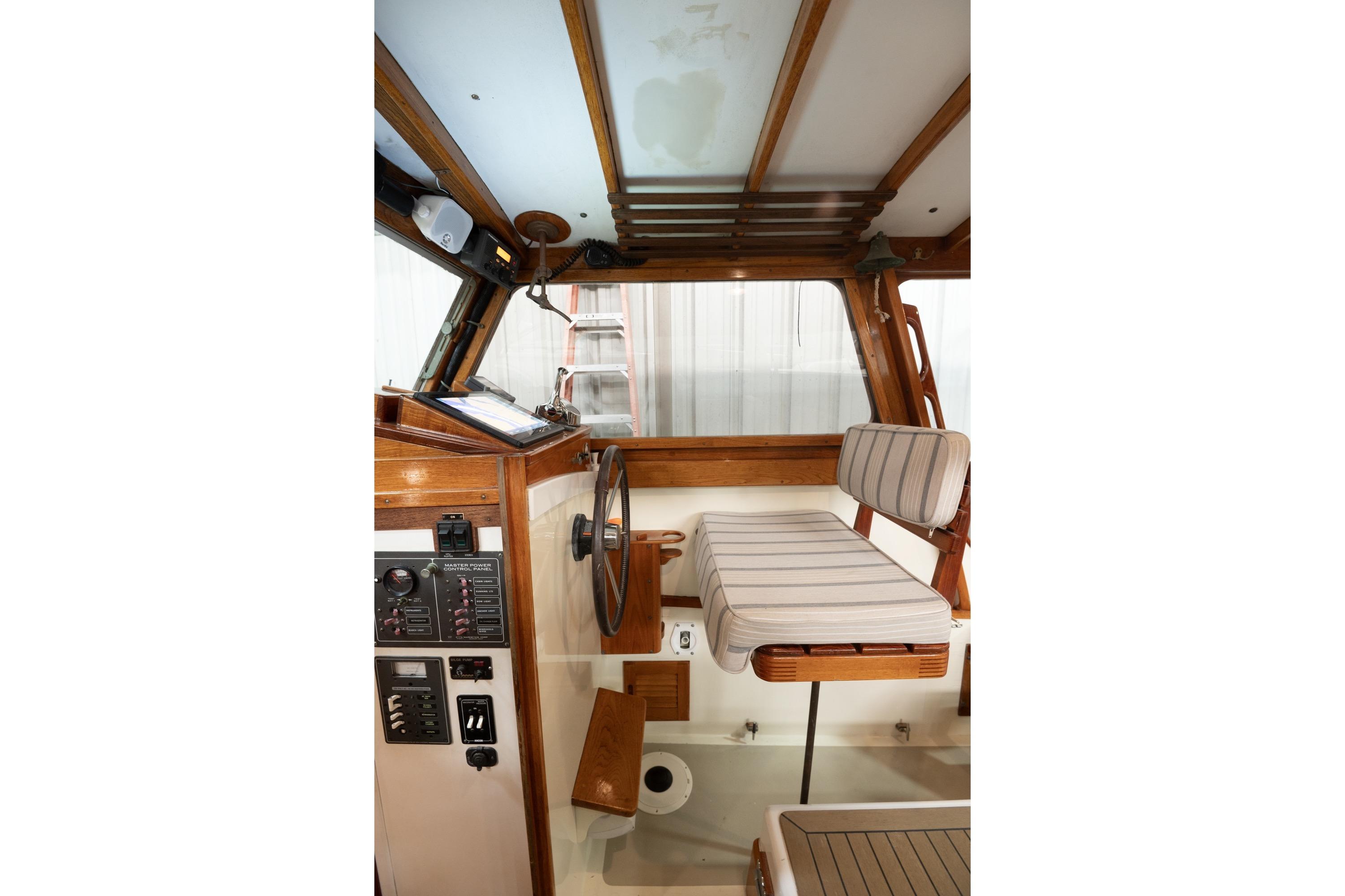 1986 Dyer Hardtop boat interior with wooden helm, striped seating, and control panel.