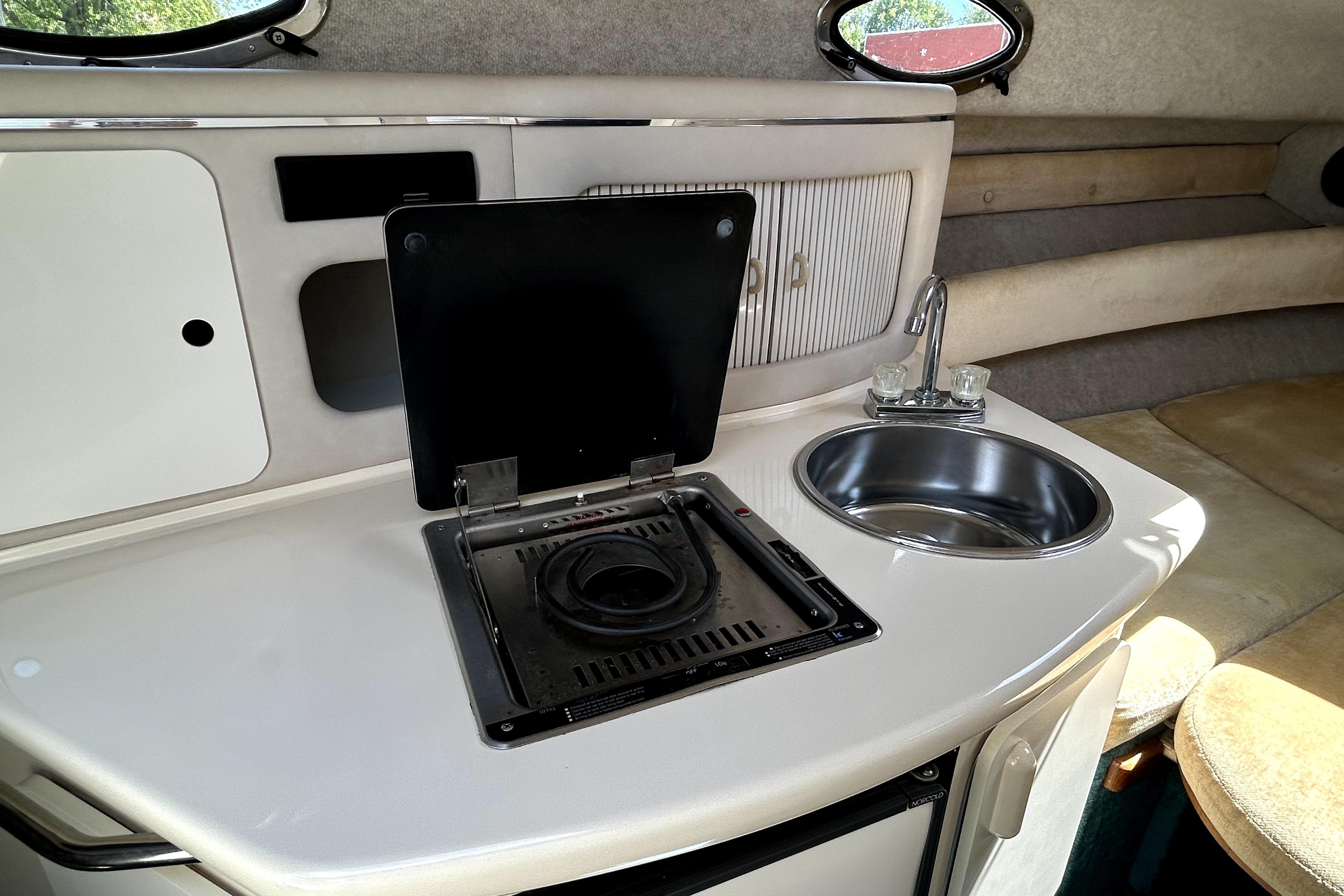 Interior of 1995 Sea Ray 250 Sundancer with kitchenette, stove, and sink.