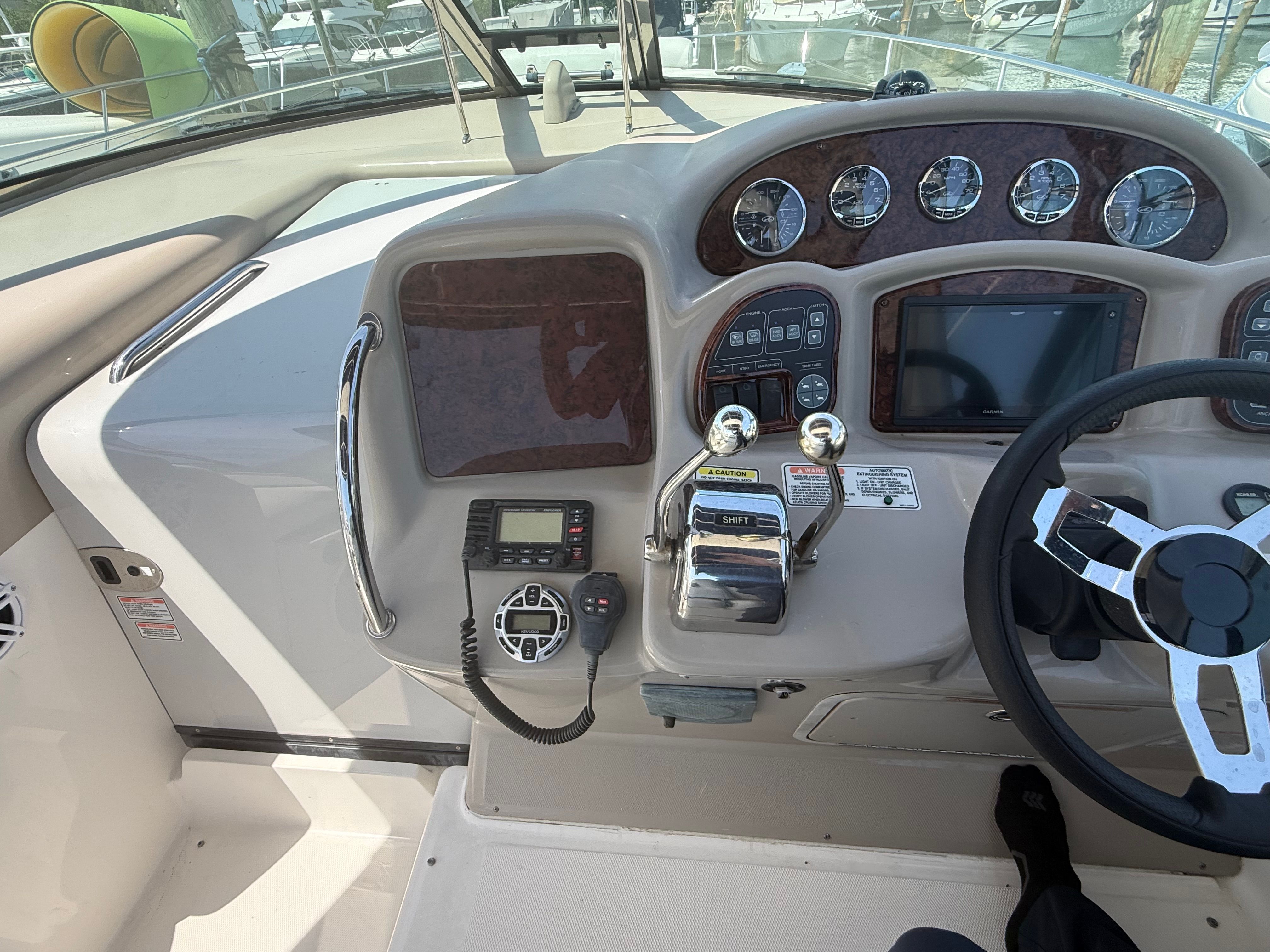 The cockpit of a 2006 Sea Ray Sundancer 320 with steering wheel, instruments, and throttle controls.