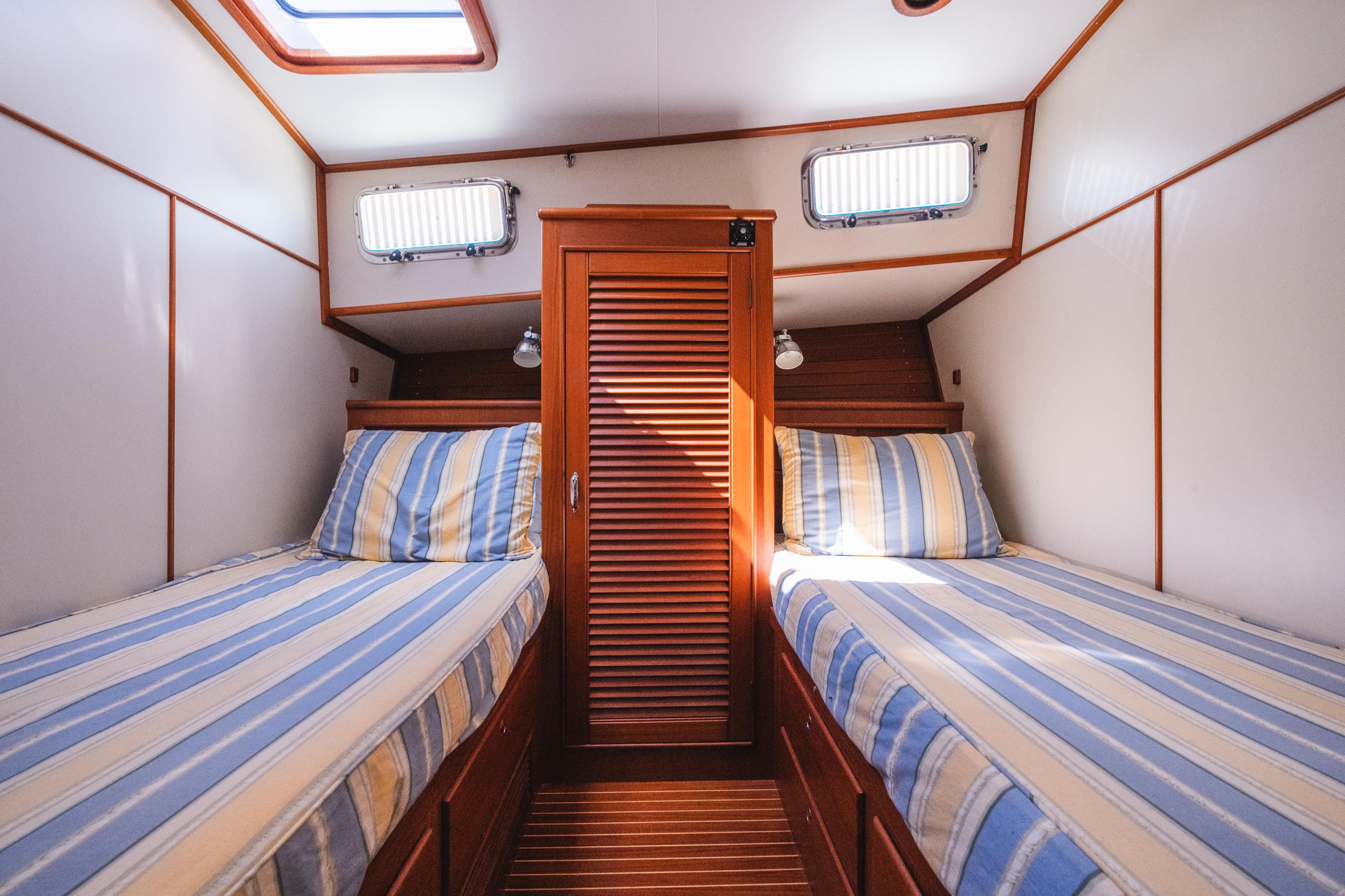 Cabin interior of 1999 Grand Banks 49 Eastbay HX with twin beds and striped bedding.