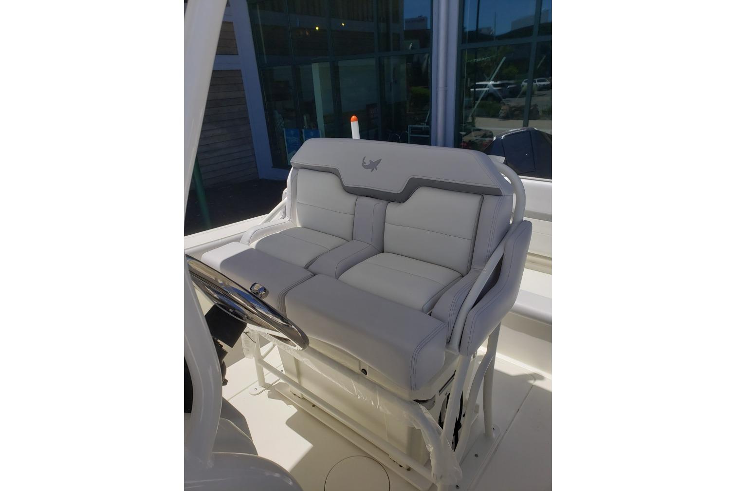 2026 Mako 226 Center Console boat with plush white seating and steering wheel.