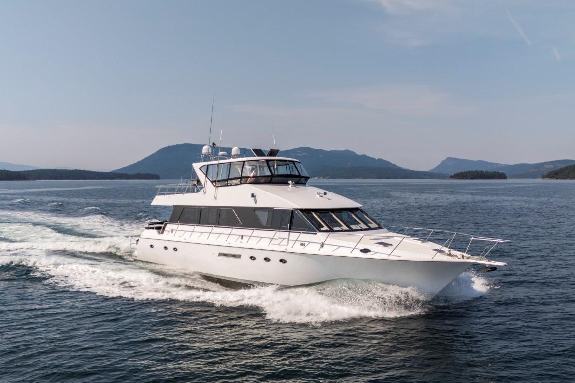 Luxury 1996 Forbes Cooper 73 yacht cruising on open water with scenic mountain backdrop.