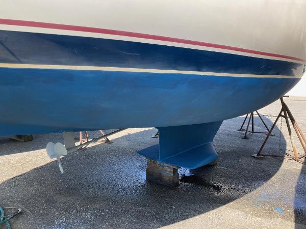 1989 Catalina 30 sailboat hull and keel on stands, blue and white paint.