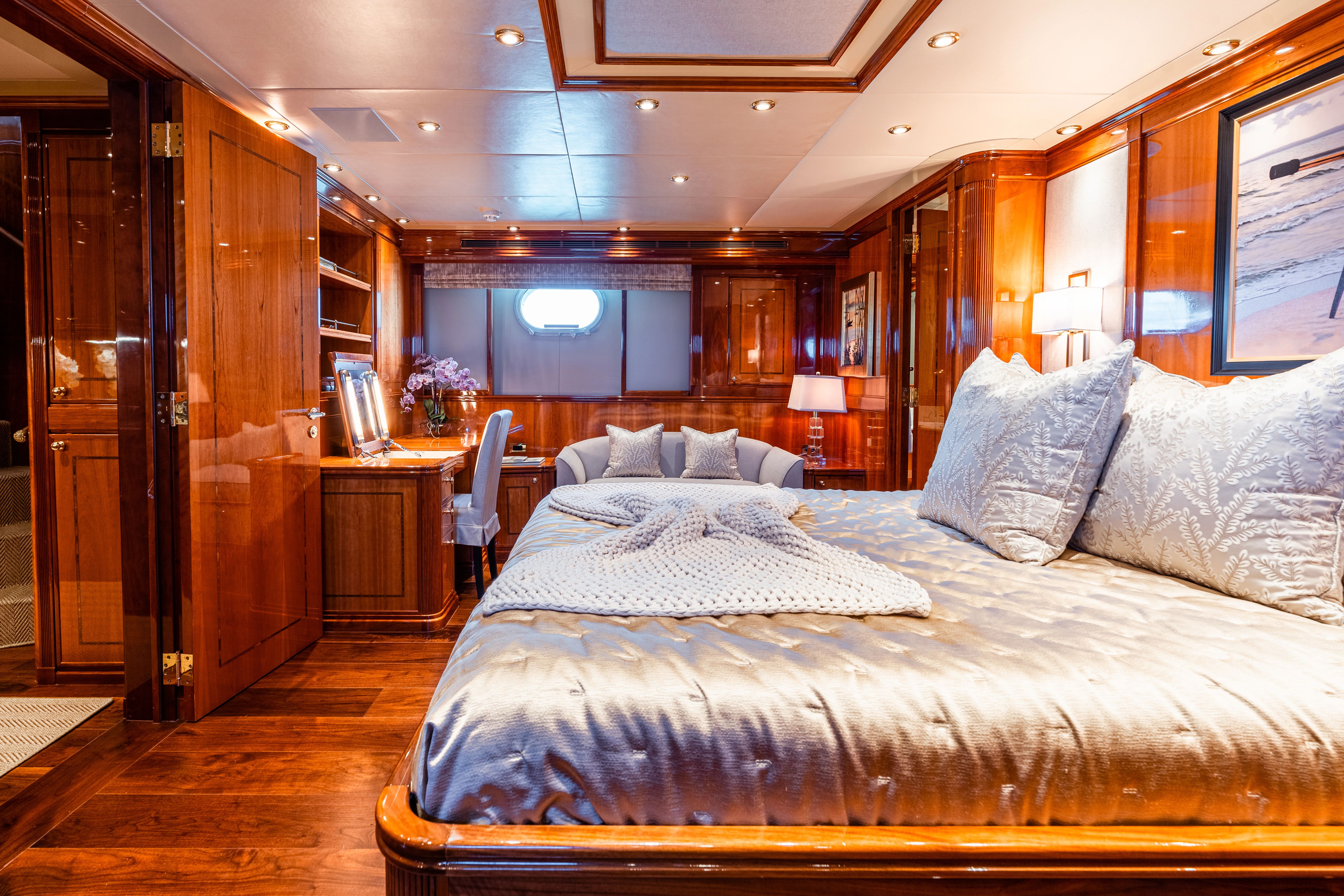 Luxurious yacht bedroom with wooden furnishings, a large bed, and a desk.
