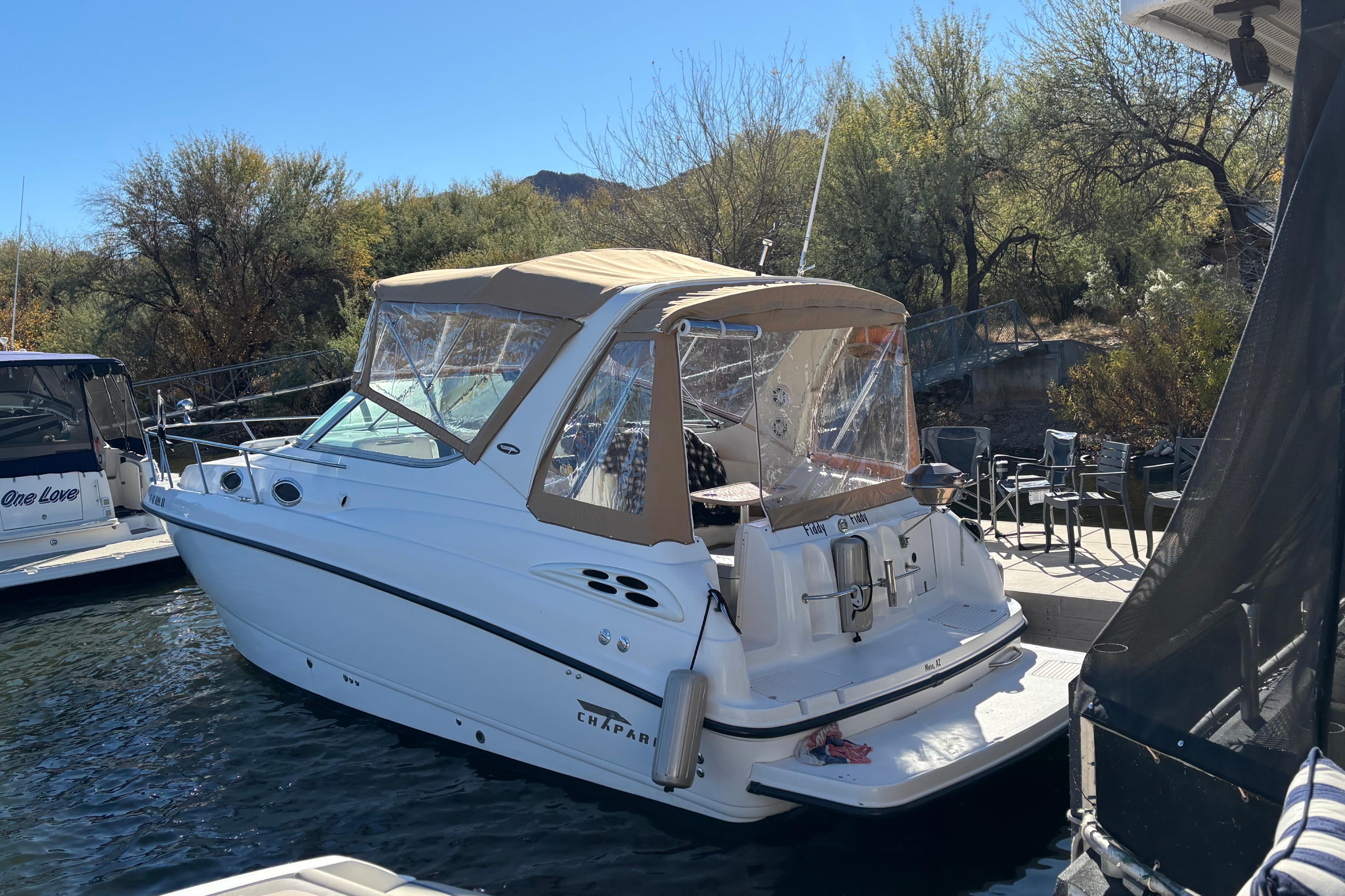 1999 Chaparral Signature 300 boat docked near lush greenery.