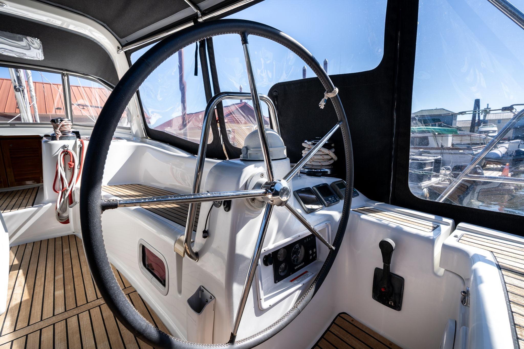 Steering wheel of 2013 Beneteau Oceanis 50 sailboat, featuring teak deck and navigation controls.