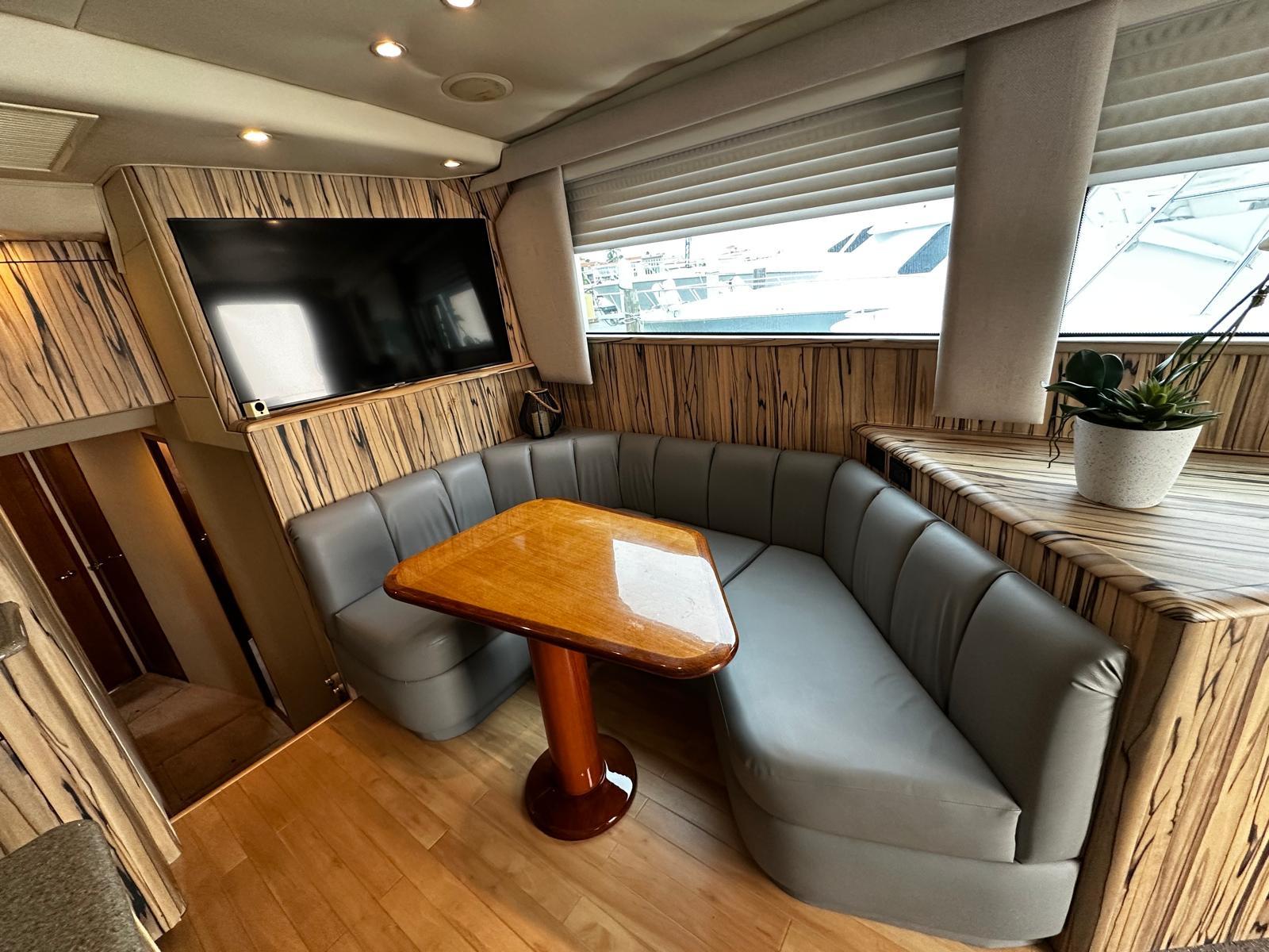 Luxurious 2003 Viking 52 yacht interior with cozy seating, wooden table, and mounted TV.