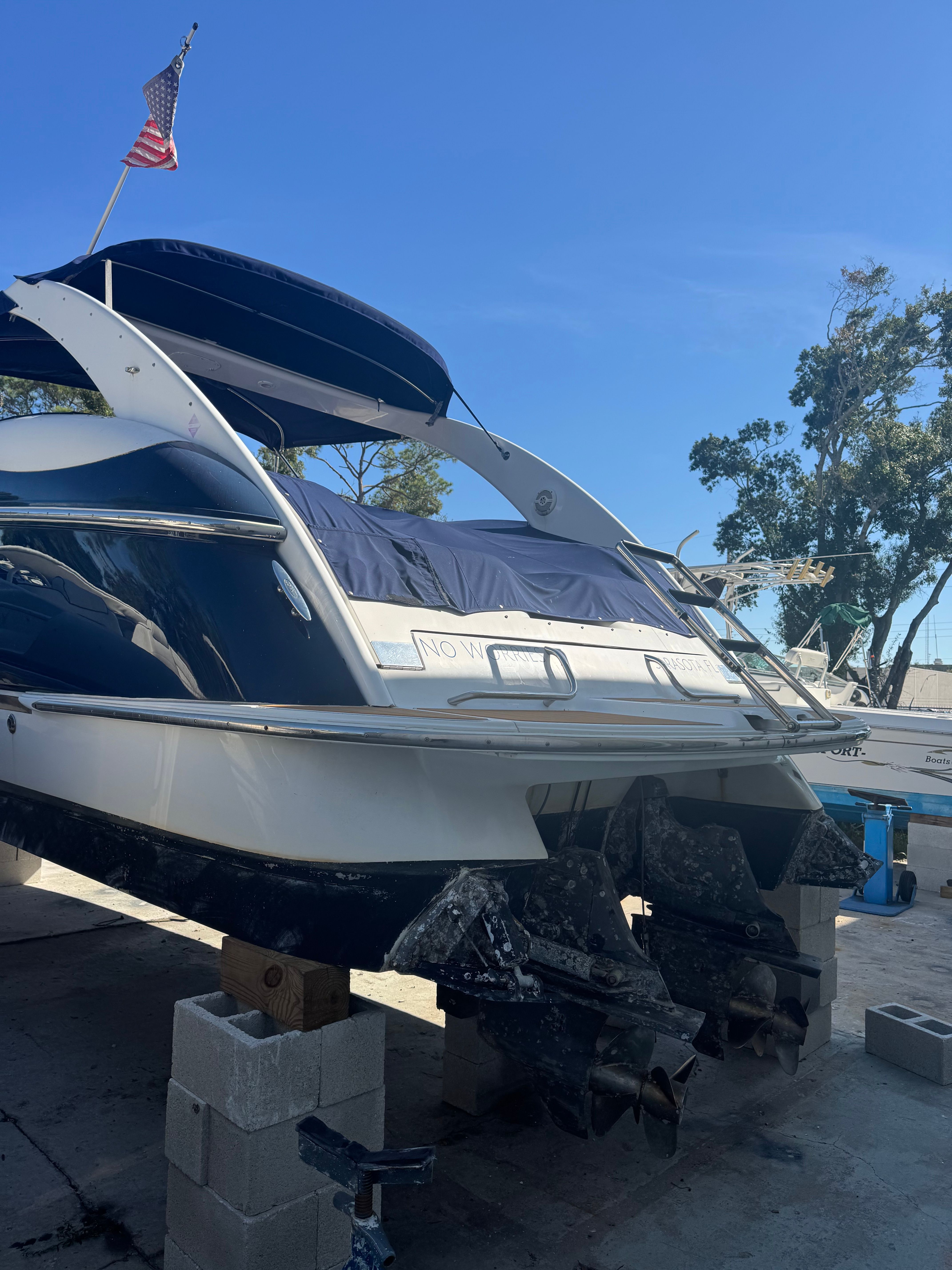 A 2003 Cobalt 360 boat is on blocks. It features a blue canopy and an American flag.