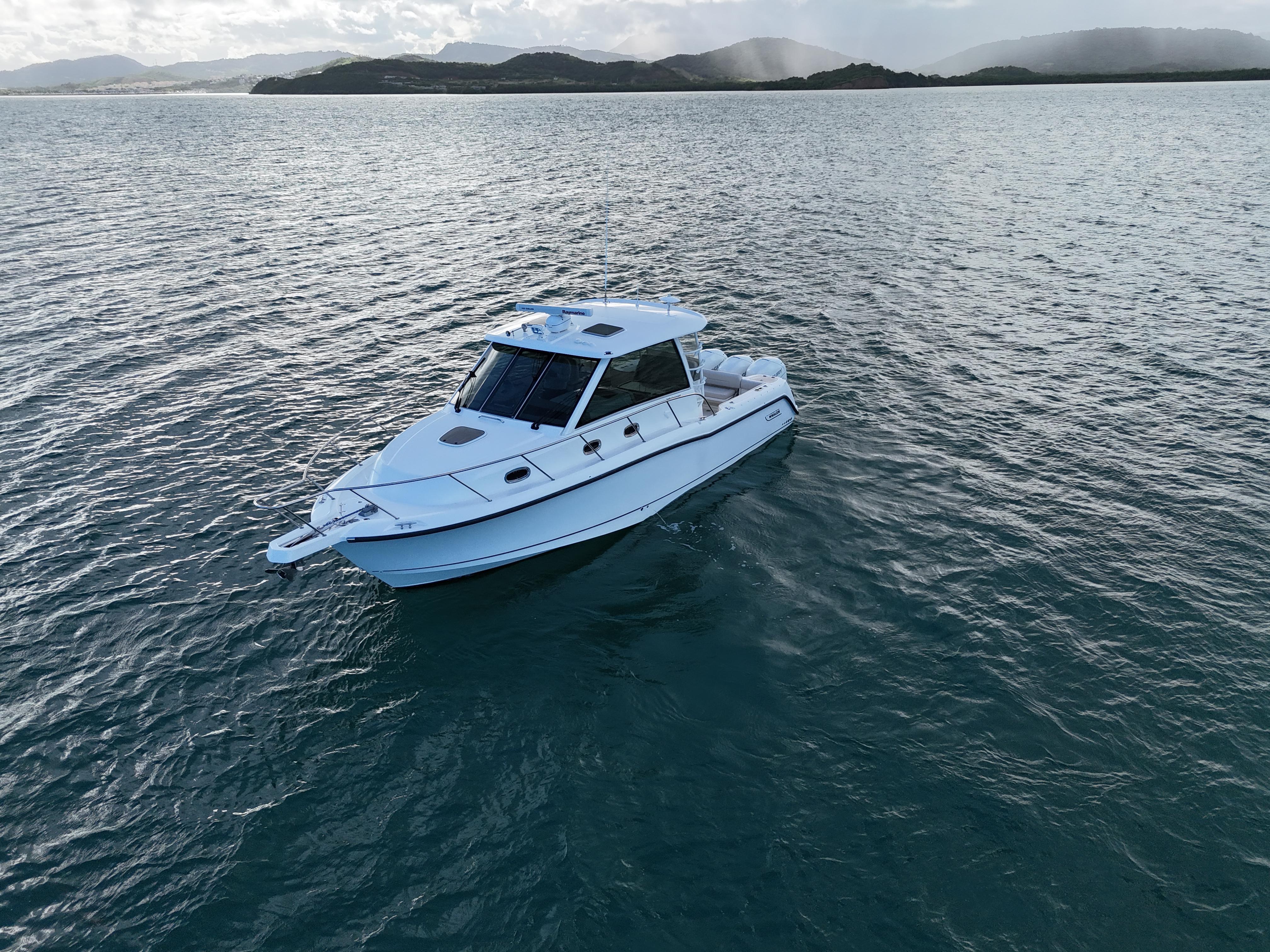 2015 Boston Whaler 345 Conquest boat on calm water with scenic background.