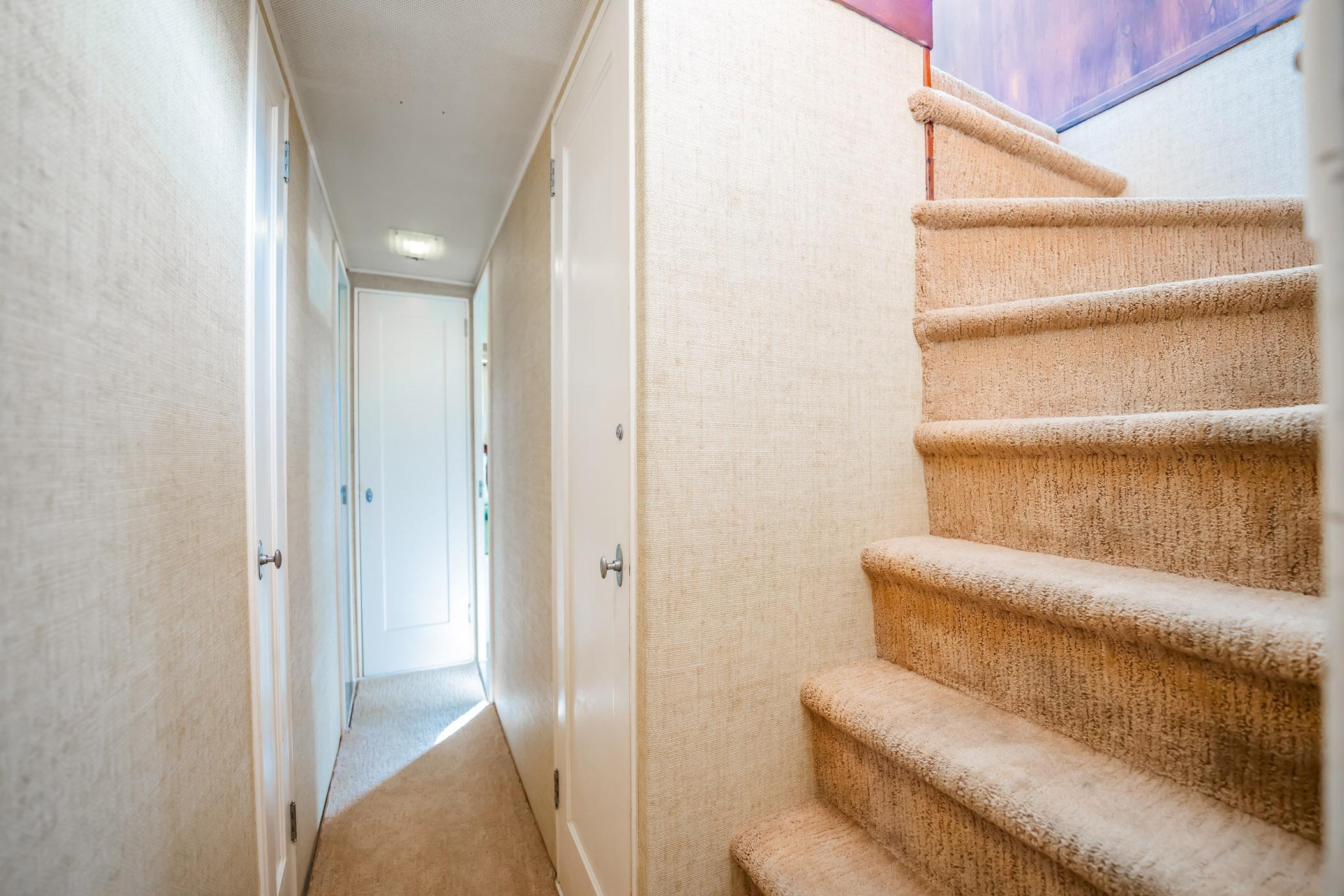 Narrow hallway and carpeted stairs inside a 1972 Trumpy 72 Motor Yacht.