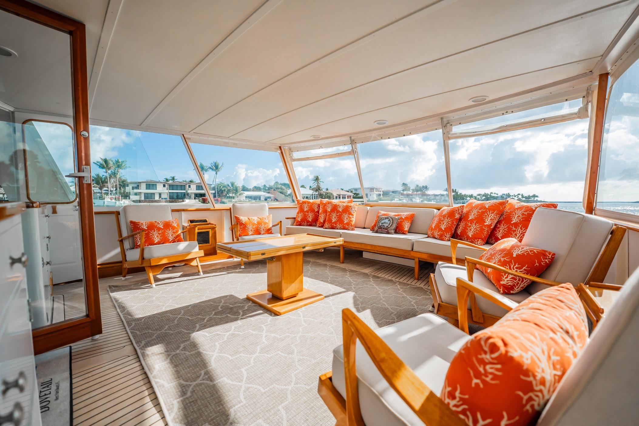 Luxurious 1972 Trumpy 72 Motor Yacht interior with orange cushions and panoramic windows.