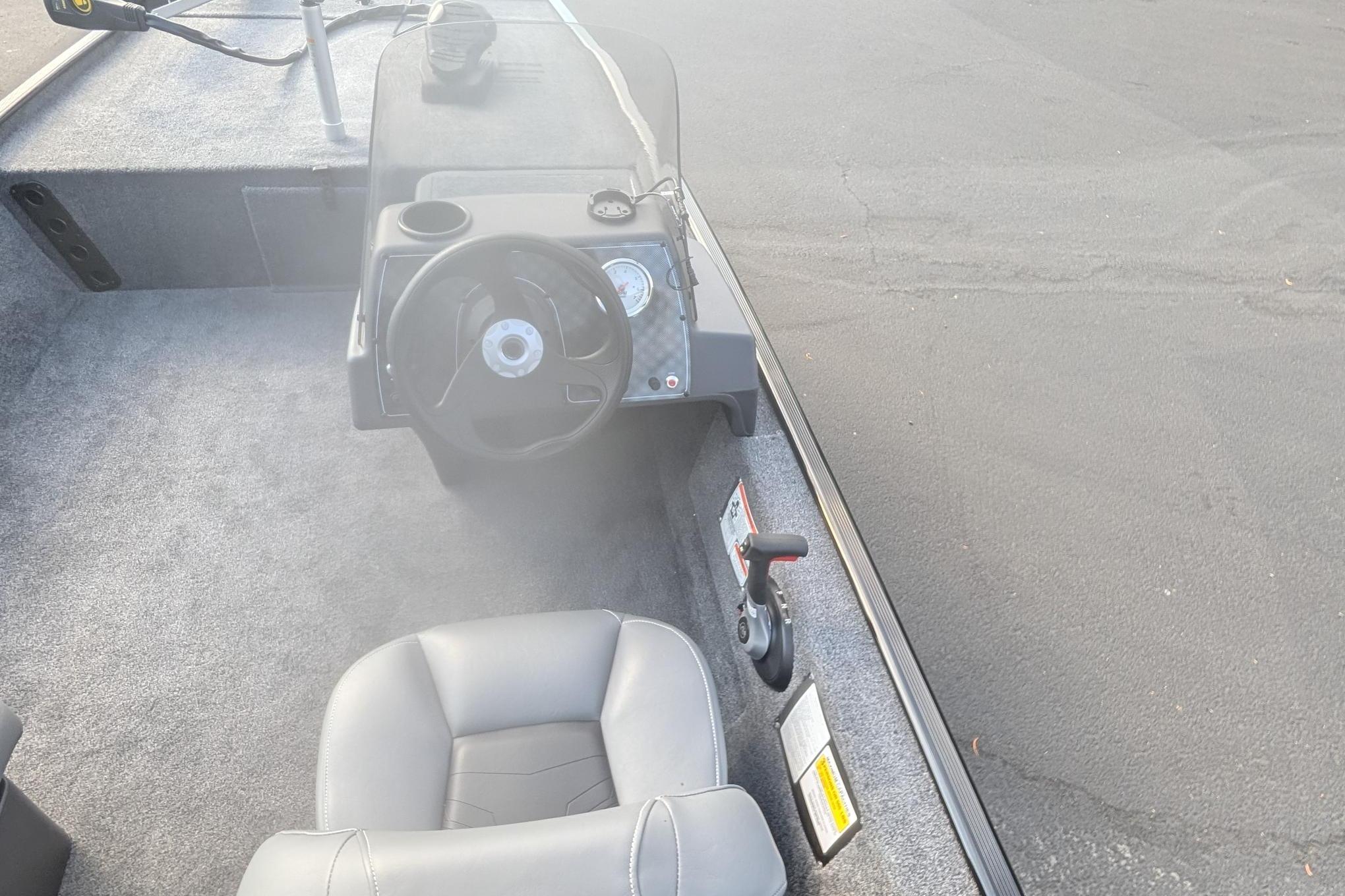Interior view of 2026 Tracker Bass Tracker Classic XL boat cockpit with steering wheel and seat.