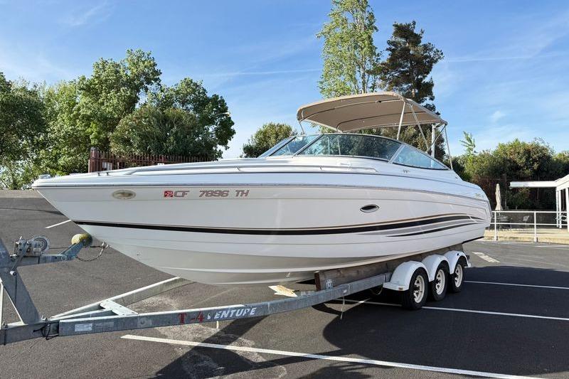1999 Formula 280 Sun Sport boat on trailer in parking lot.