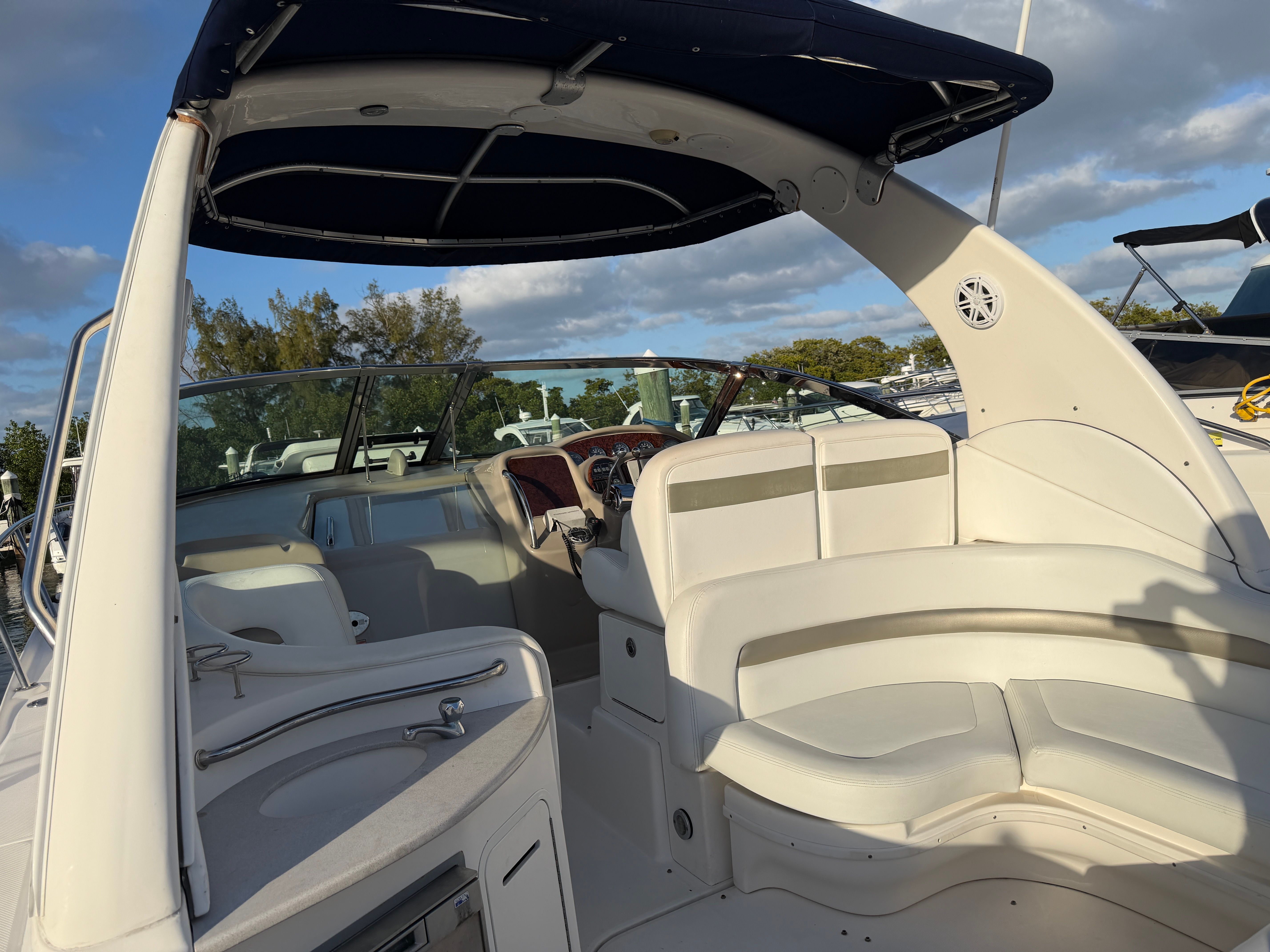 The image shows the cockpit of a 2006 Sea Ray Sundancer 320 with white seating and a blue canopy.