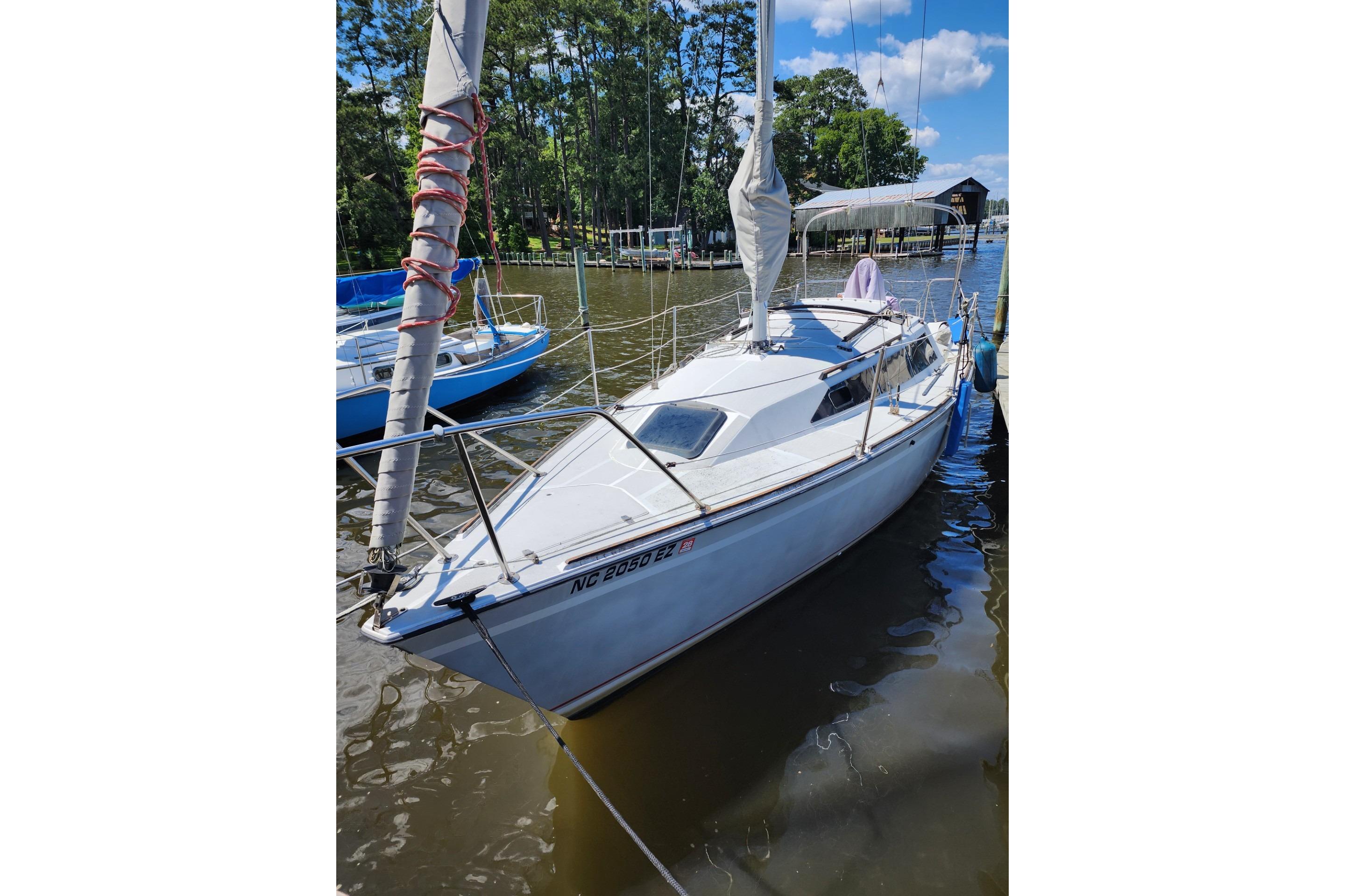1988 O'Day 272 LE sailboat docked on a sunny day, surrounded by trees.
